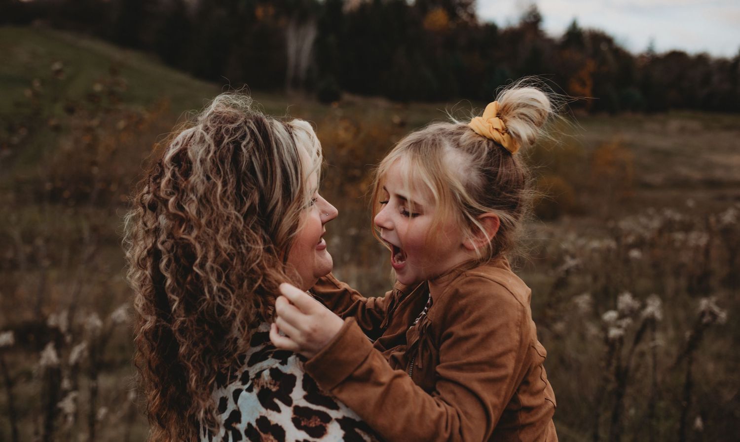 Mother and daughter sharing a surprised, joyful expression during an outdoor fall photo session.