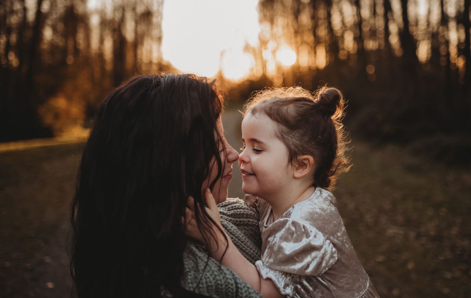Sweet mother and toddler daughter sharing a loving nose-to-nose moment during golden hour outdoor session.