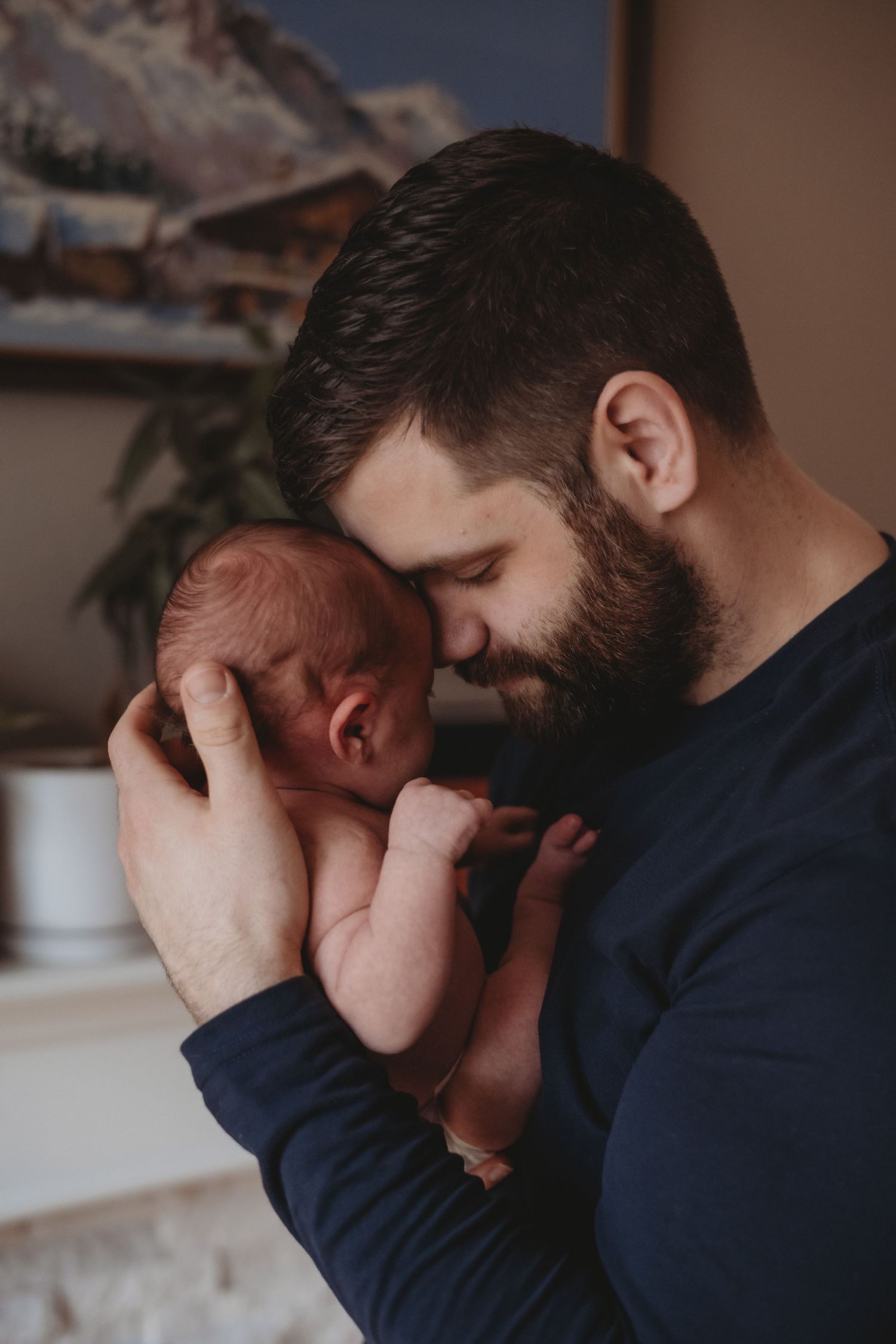 Bearded father tenderly holding his newborn baby close to his face with love.
