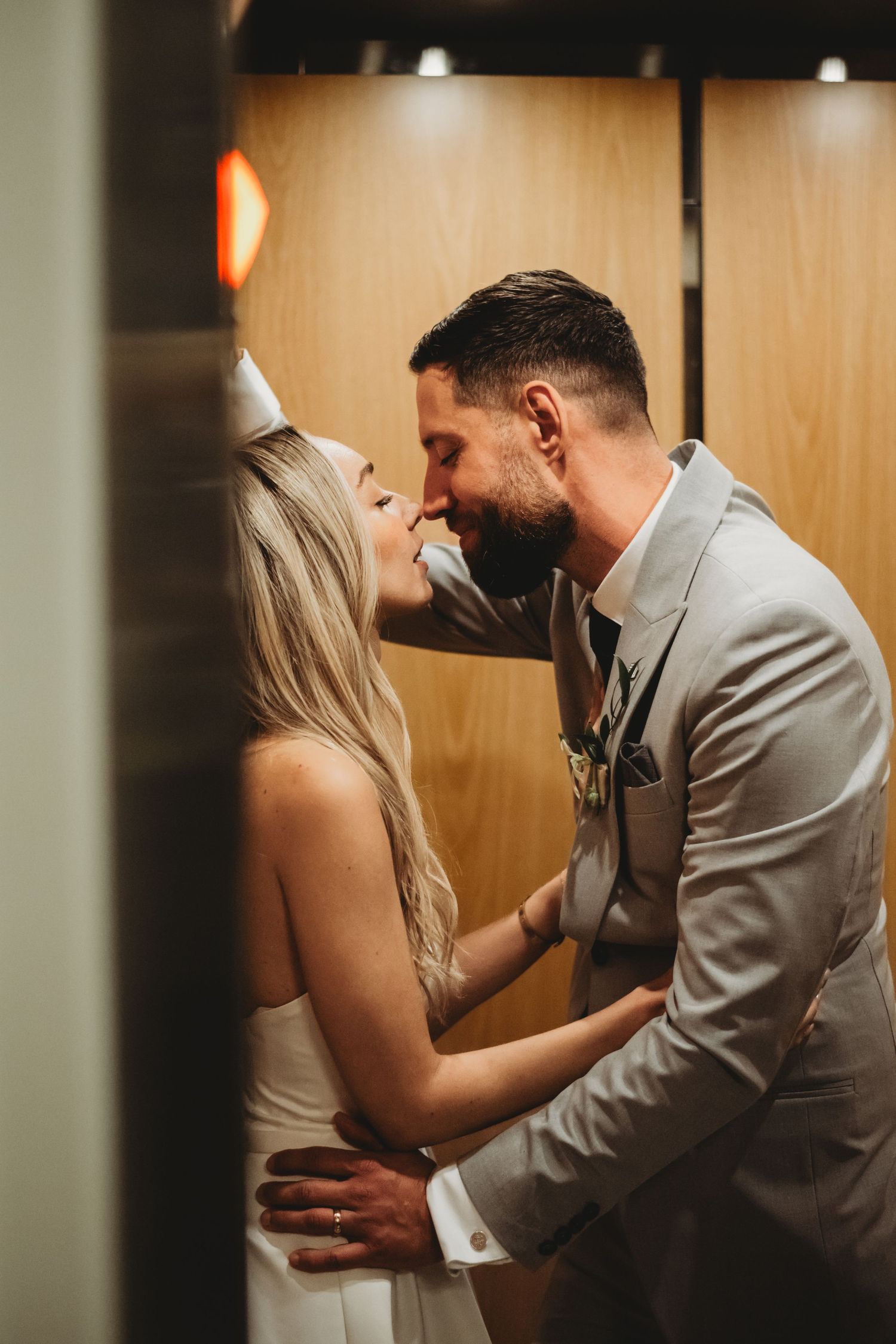 Bride and groom share a tender almost-kiss moment inside a wooden elevator.