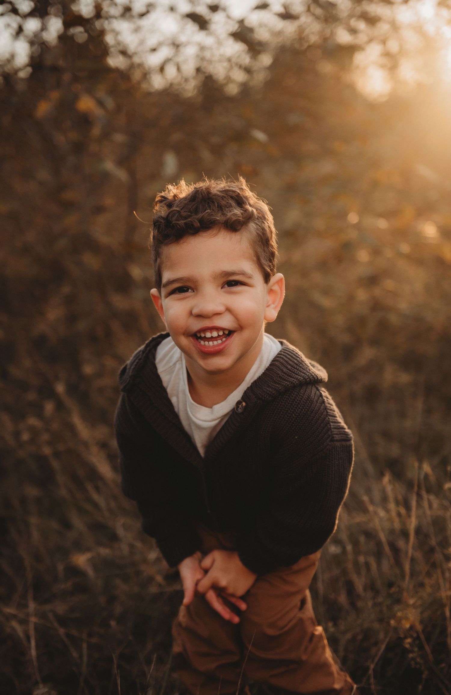 Happy young boy smiling in a sunlit autumn field.