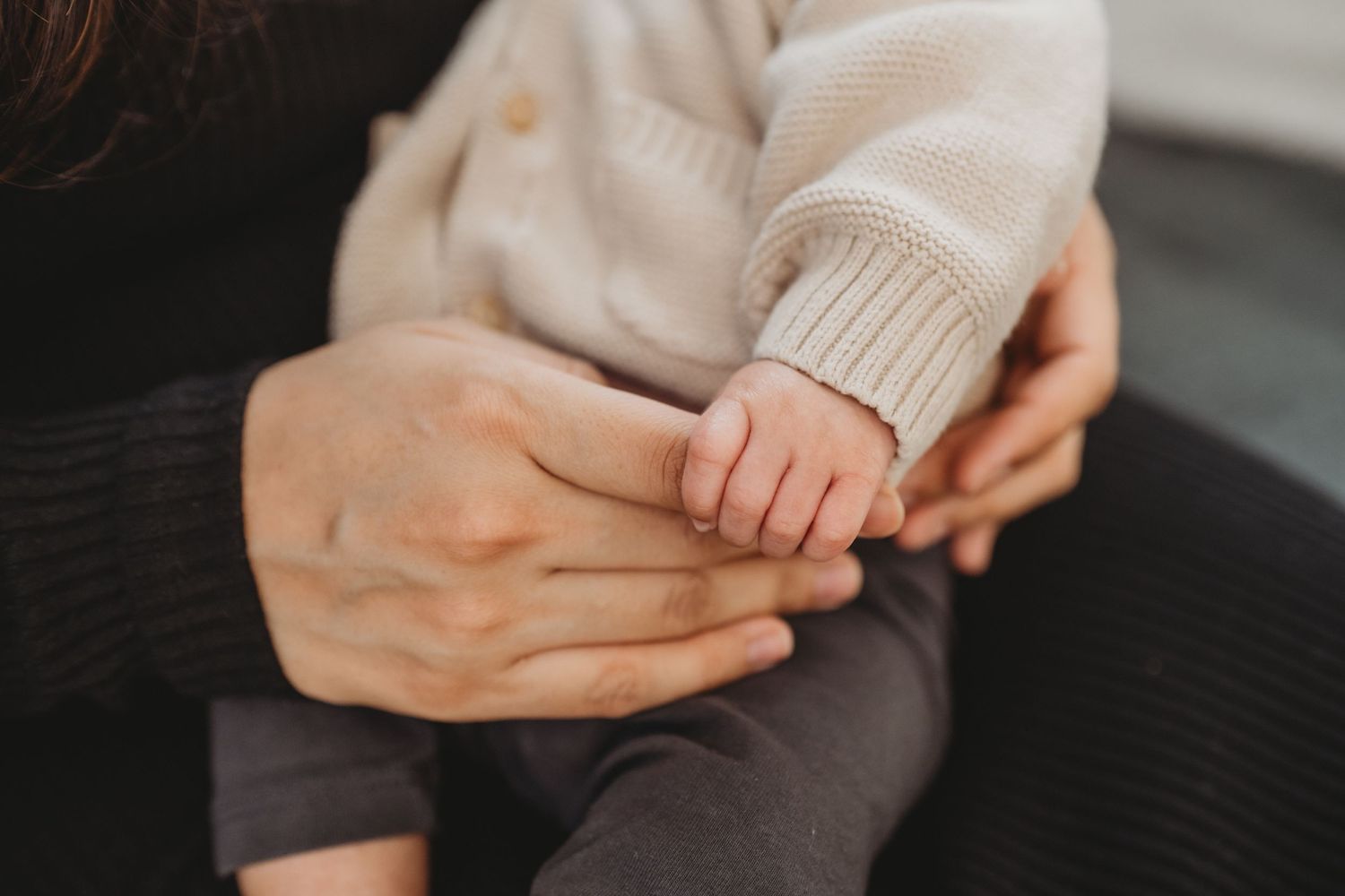 Close-up of newborn baby hand gently gripping parent fingers.