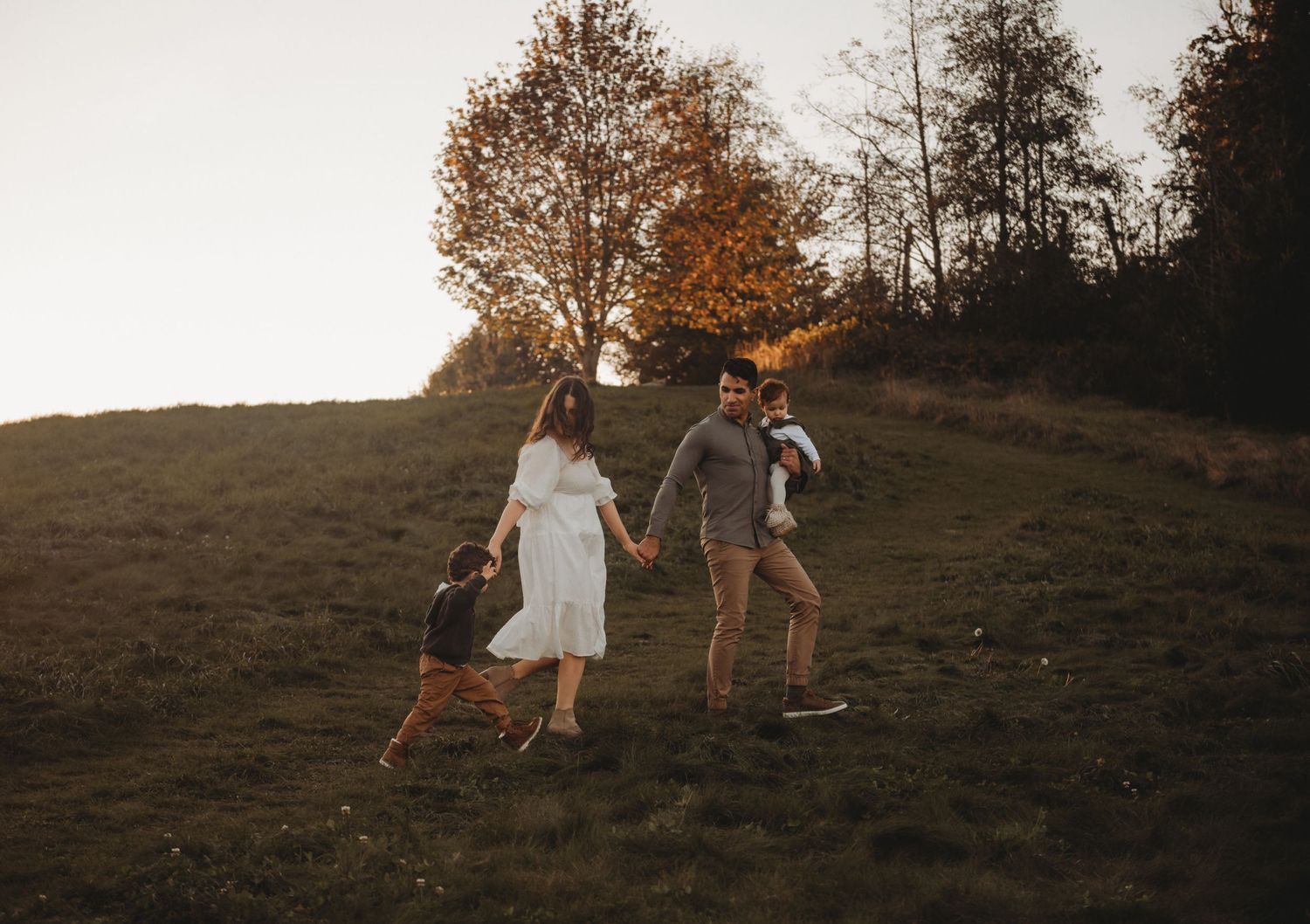 Family walking together on a hill during autumn sunset.