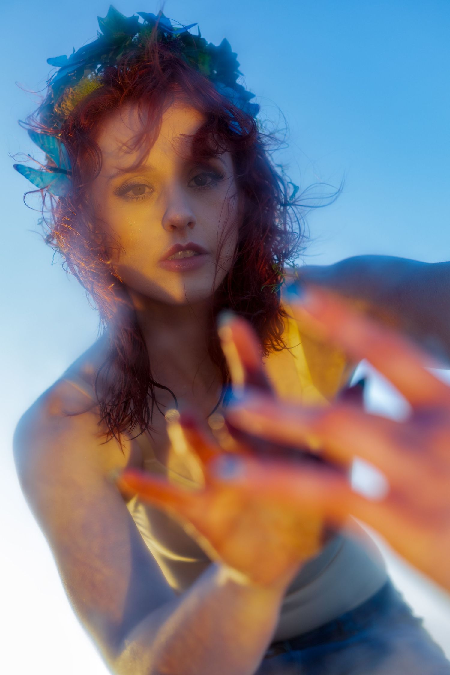 Creative cinematic portrait of a model, at golden hour, touching a mirror portal.