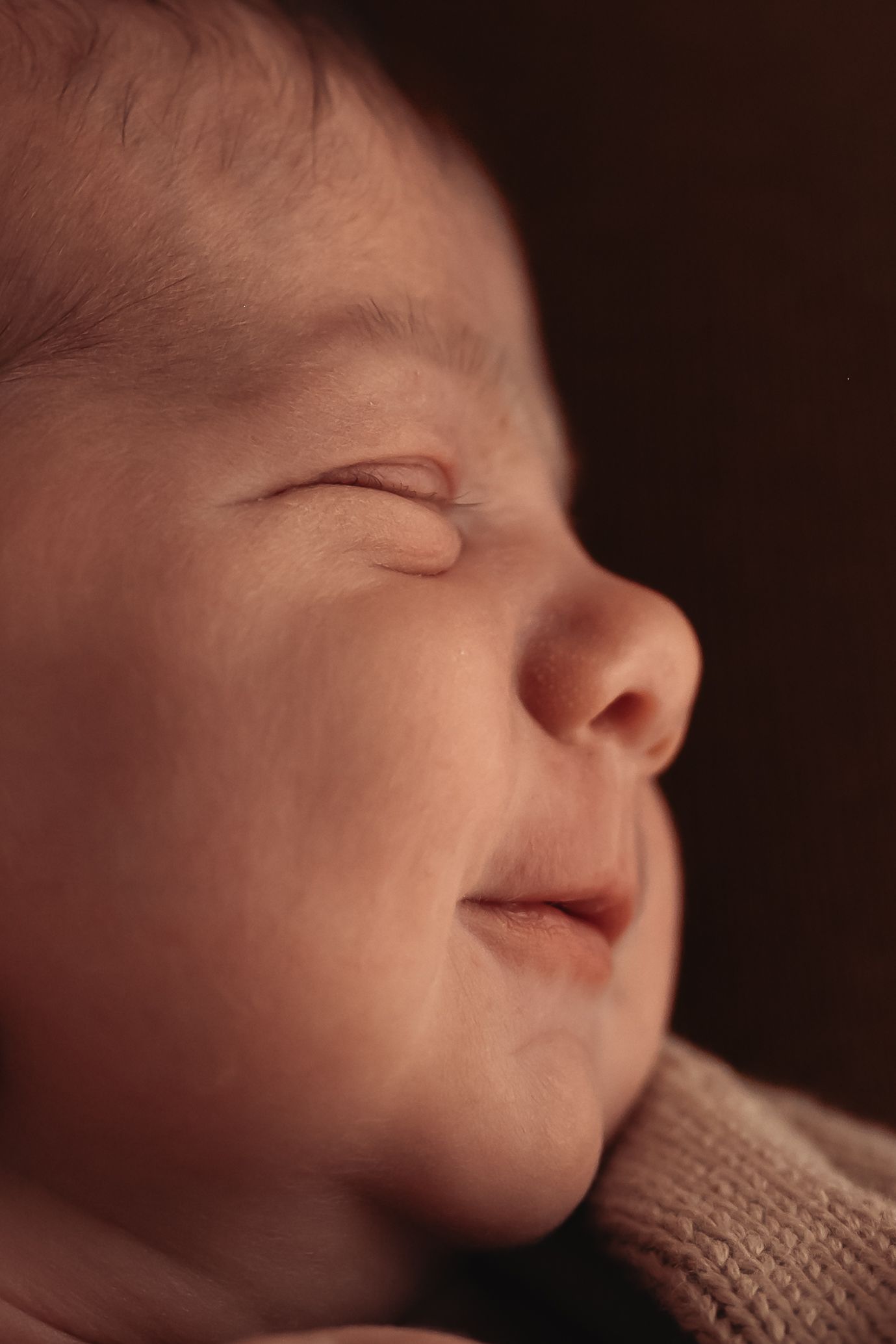 Close-up side profile of sleeping baby showing peaceful expression and soft skin.