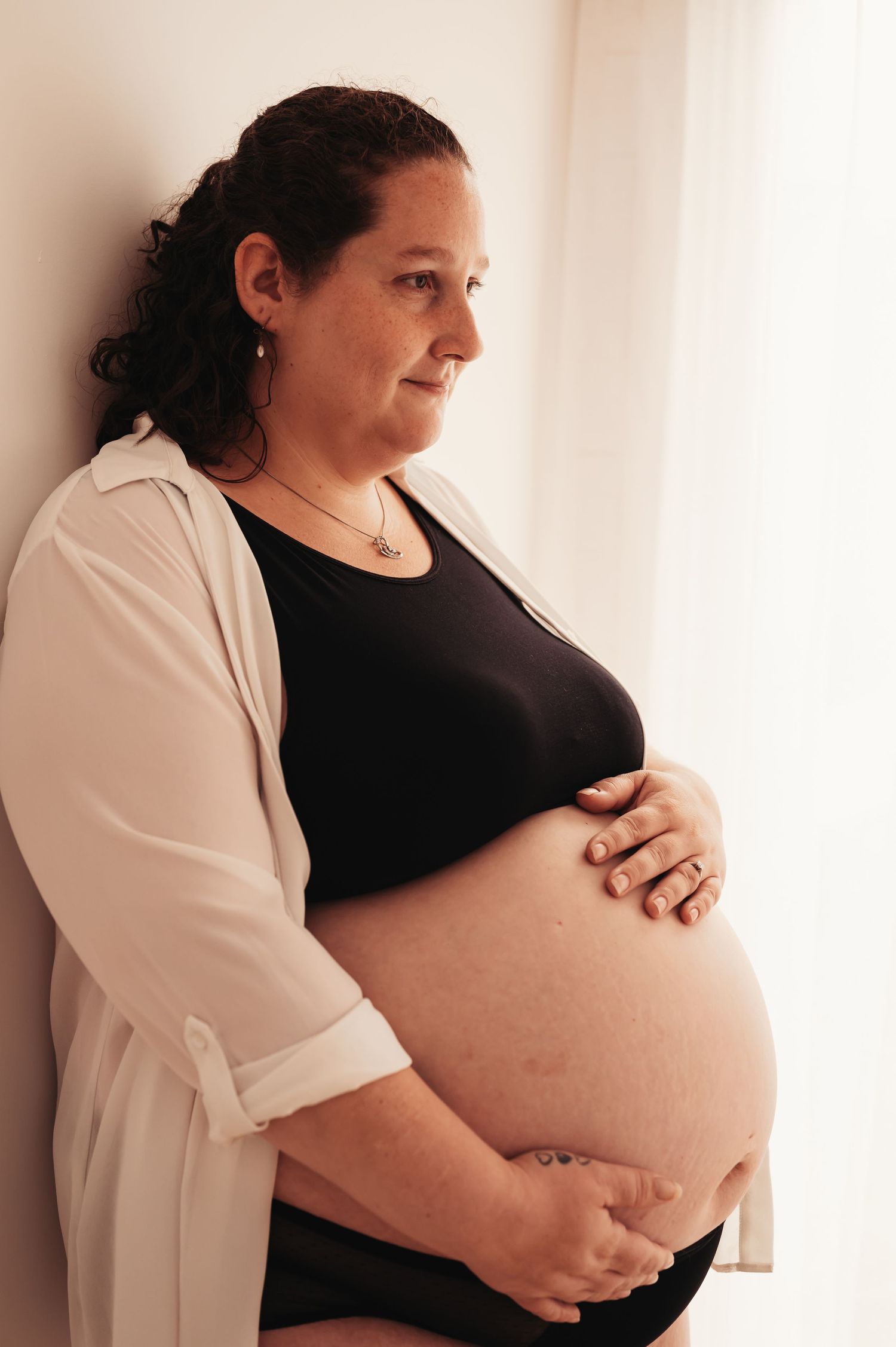 Intimate maternity portrait showing pregnant belly with hands cradling bump.