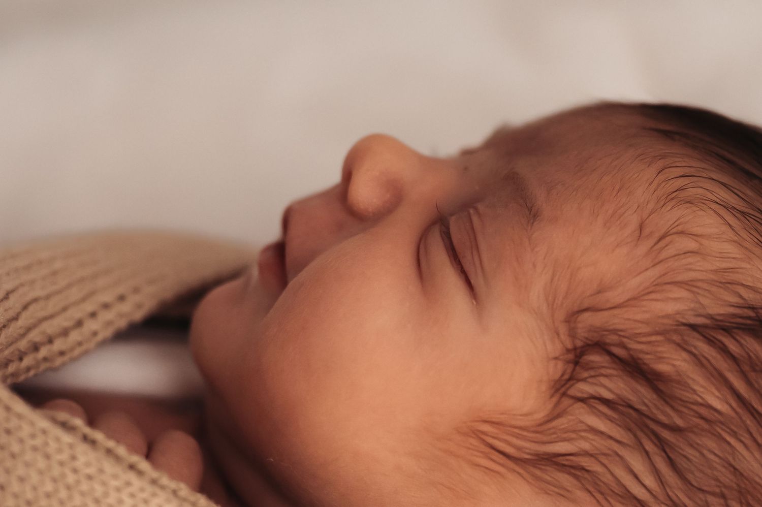 Peaceful sleeping newborn with soft lighting in profile view.