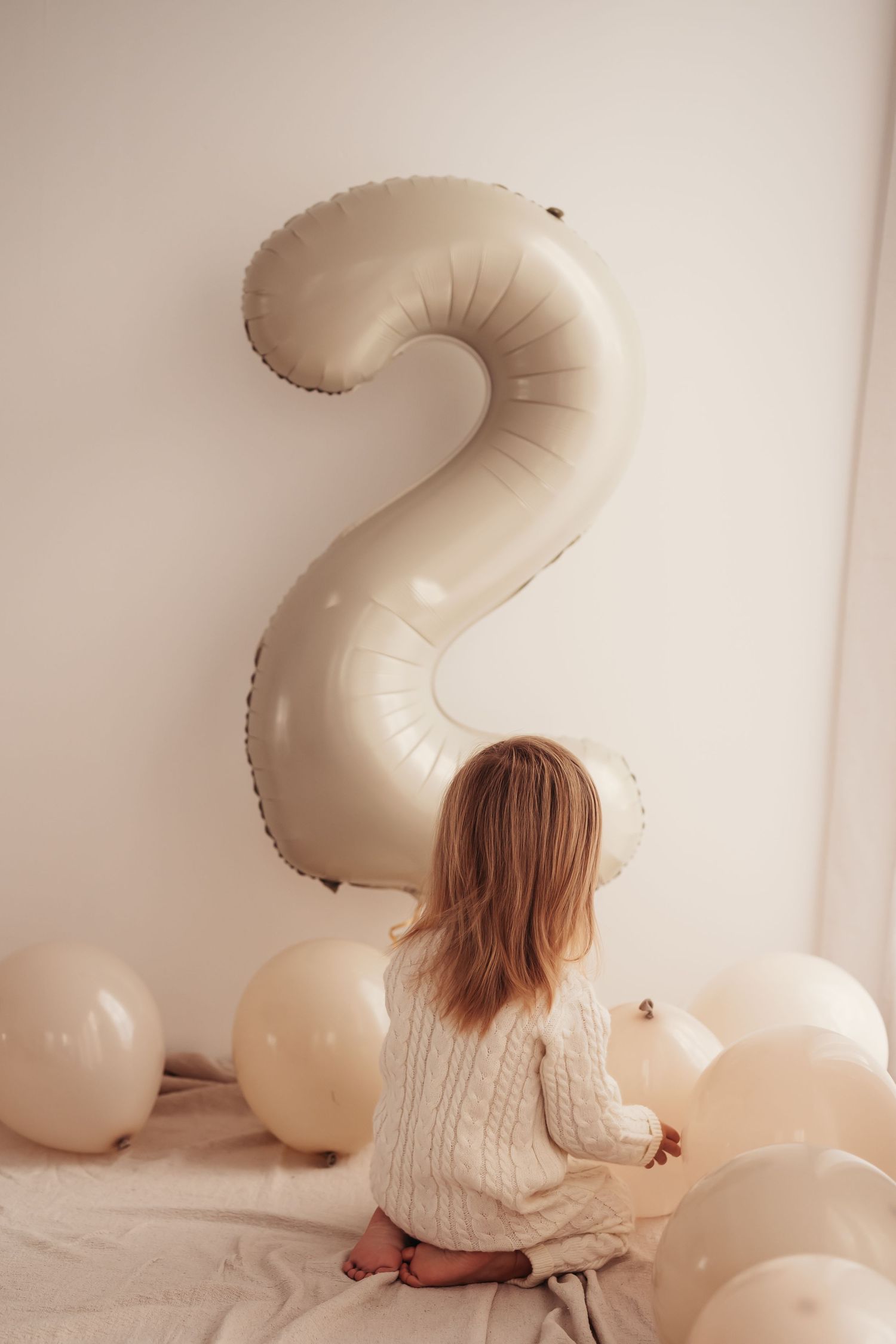 A large number 2 balloon with small white balloons for birthday decoration.