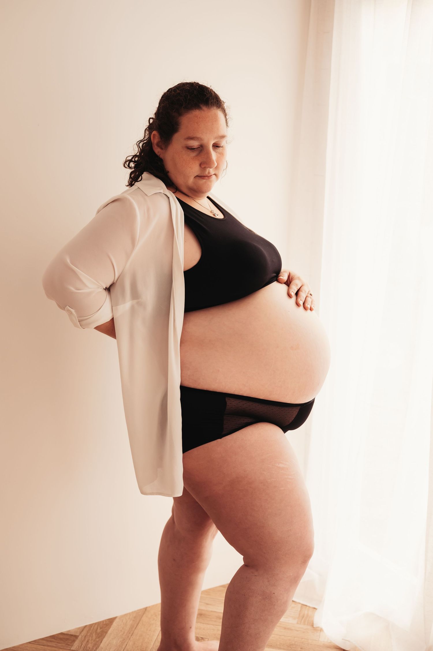 Full body maternity photo showing third trimester pregnancy in black and white outfit.