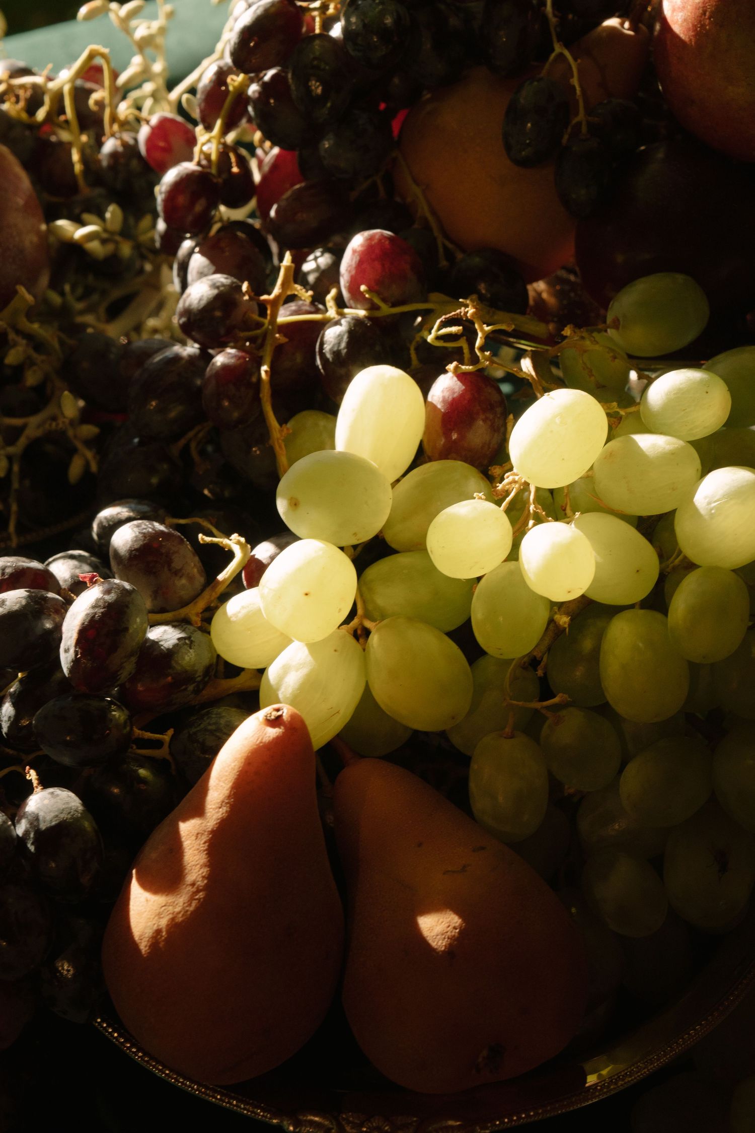Fresh red and green grapes with pears arranged in dramatic lighting.