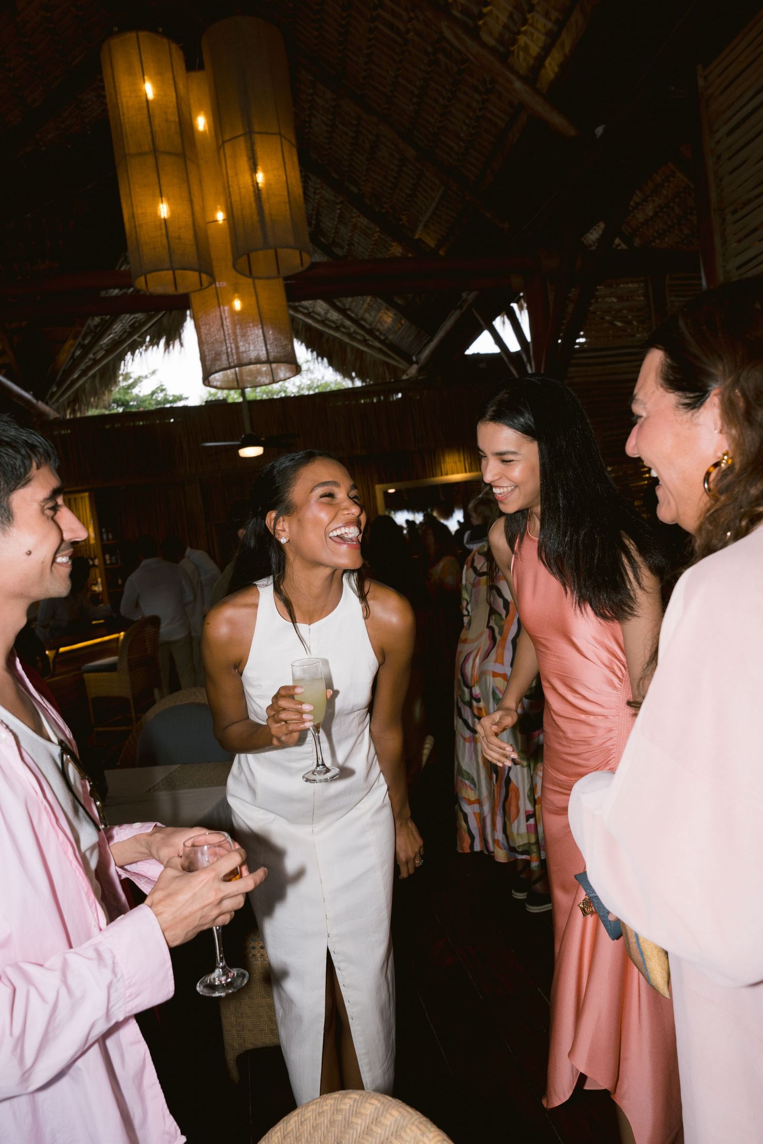 A group of people dancing and celebrating at a wedding reception in an atmospheric venue with dim lighting and a vaulted ceiling.