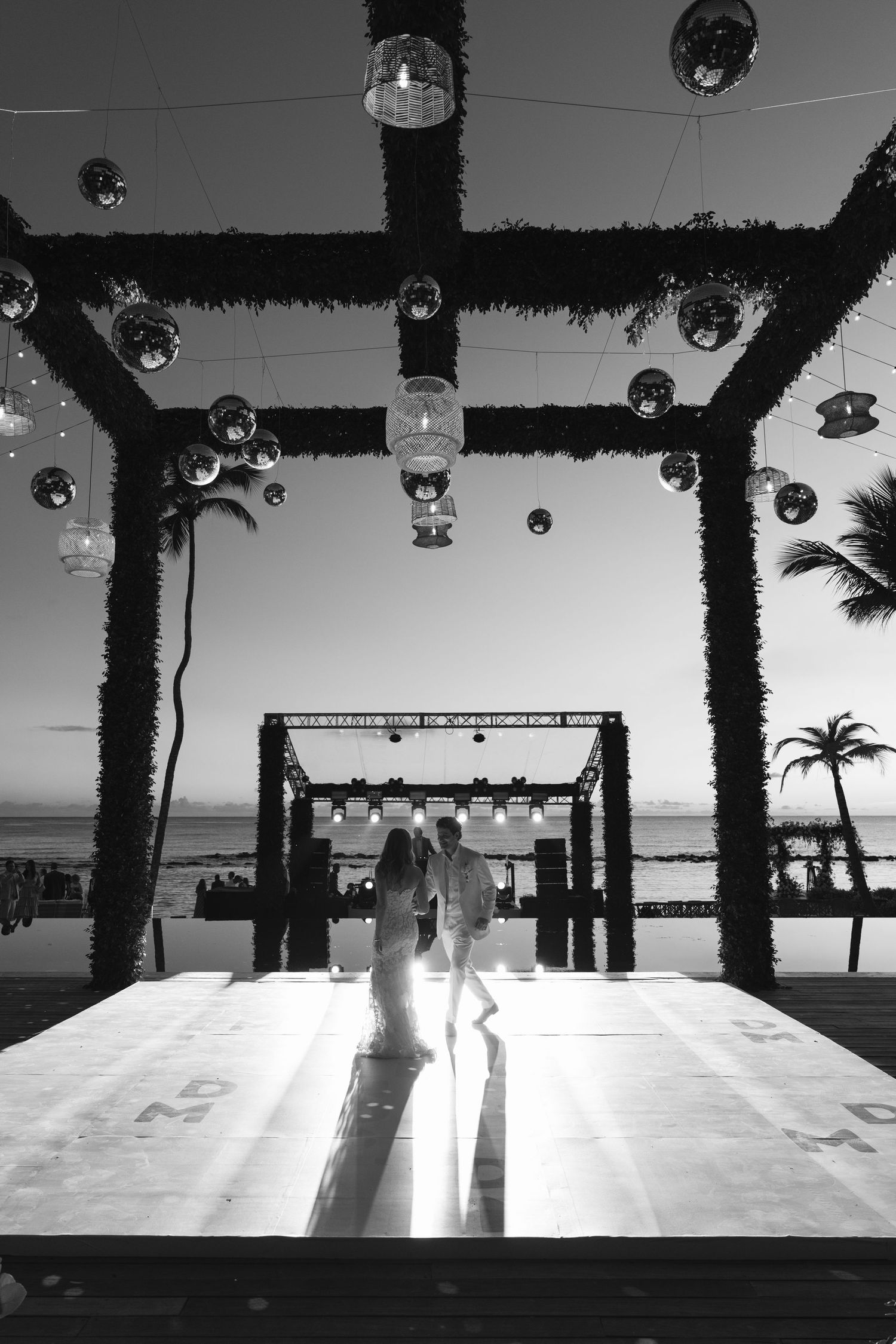 Black and white panoramic sequence showing palm trees and architectural elements against a bright sky with hanging lights.