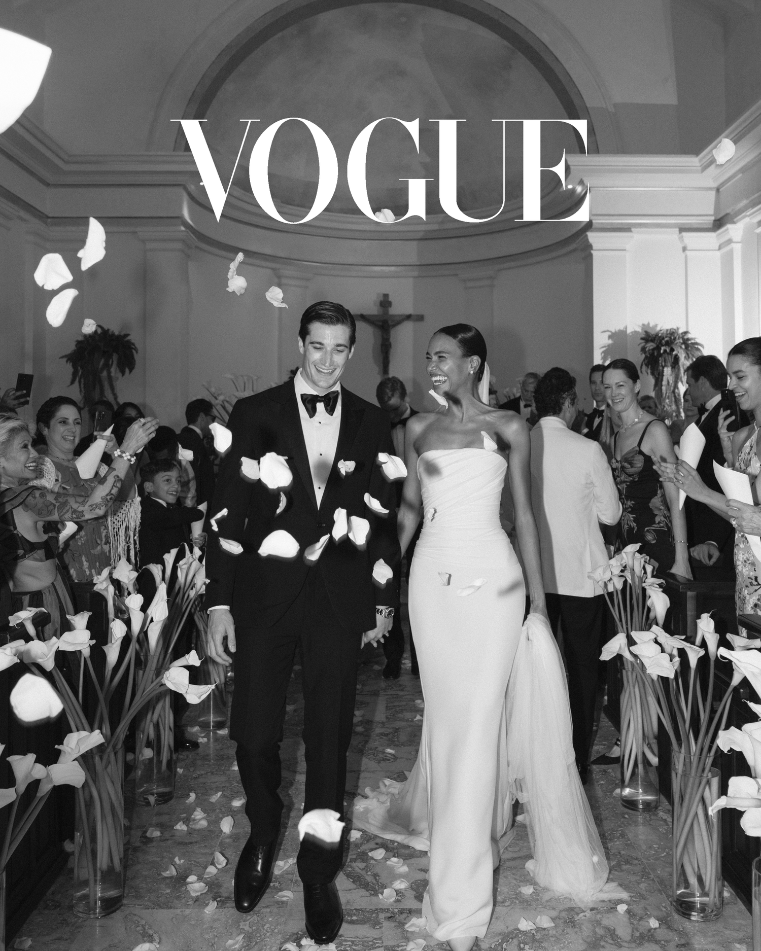 Black and white wedding party celebrating over falling petals during a reception at a grand venue.