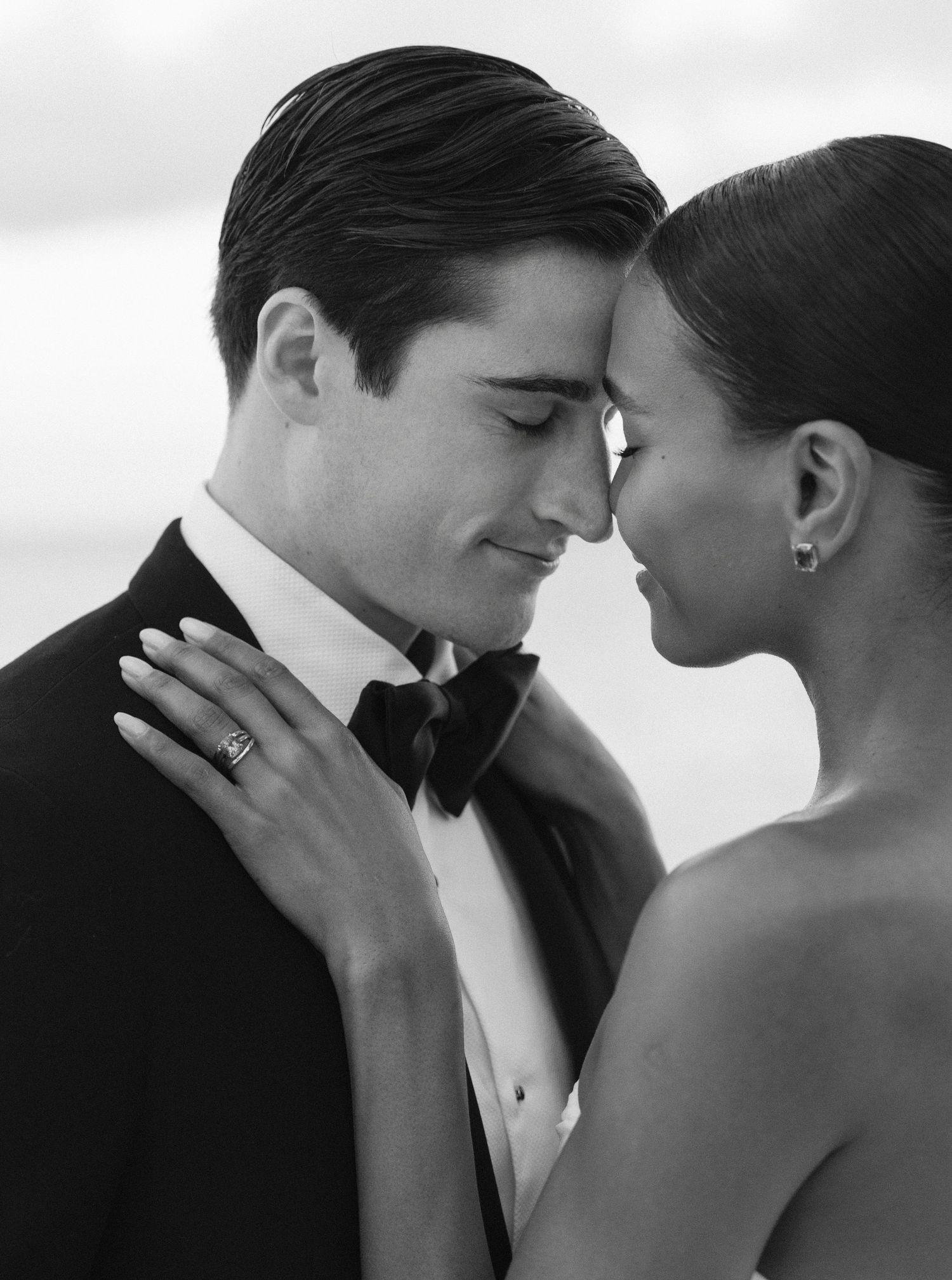 A romantic black and white photo series showing intimate moments between a couple in formal wedding attire.