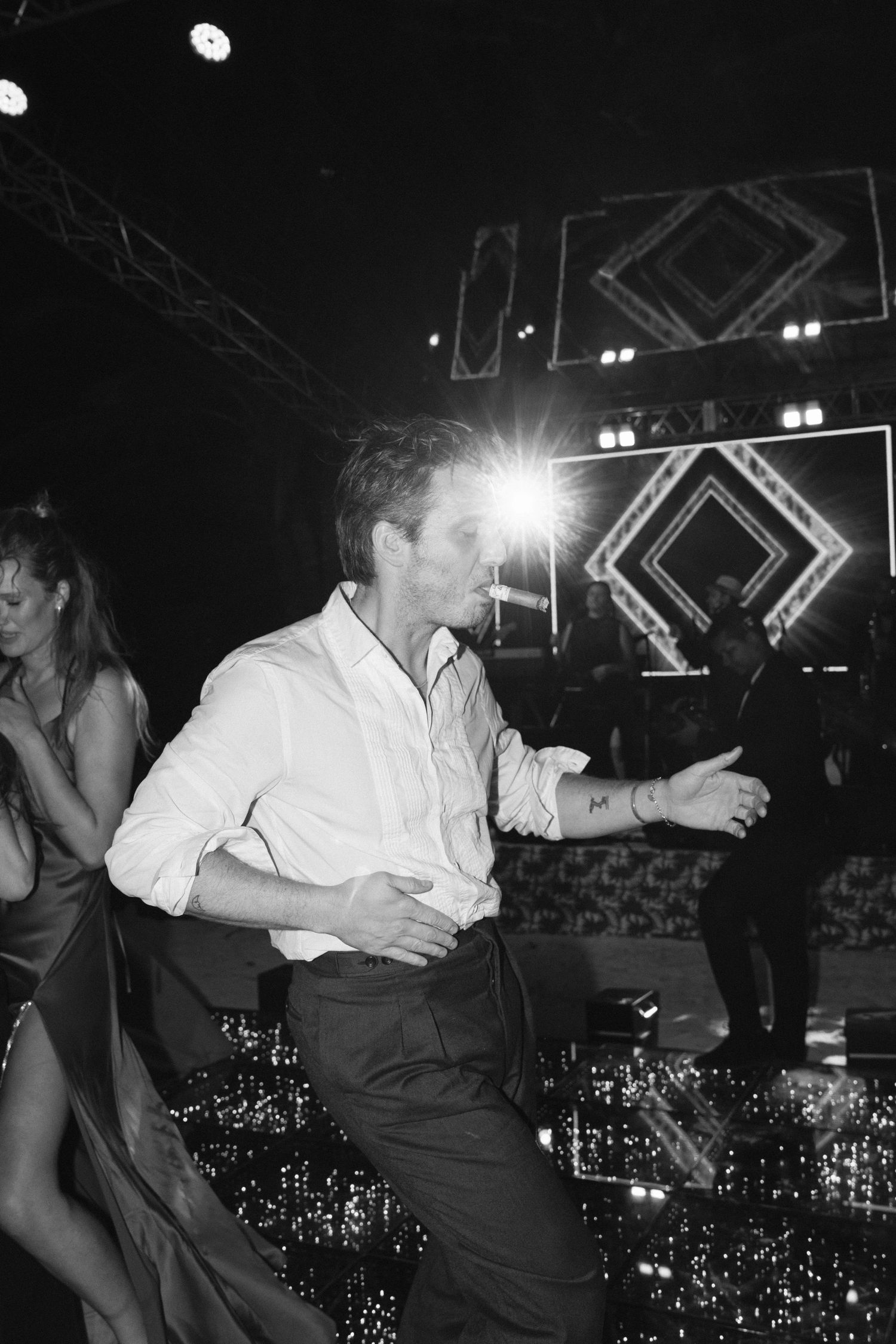 A person dancing at a nightclub with geometric lighting designs and glittery decor visible in the background.