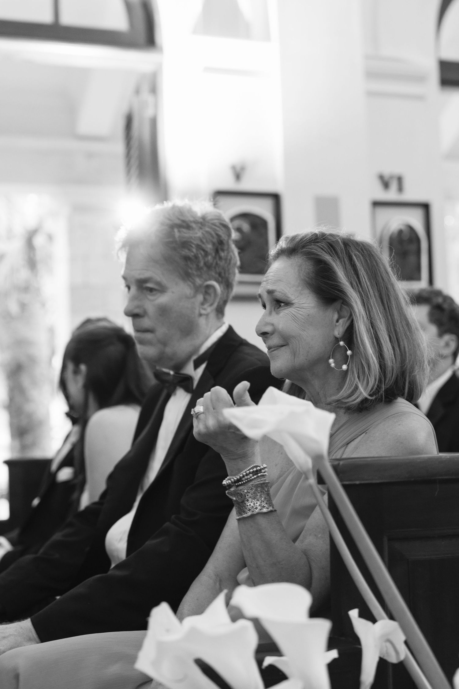 A black and white photo of two elegantly dressed guests at a formal event, seated together and smiling.