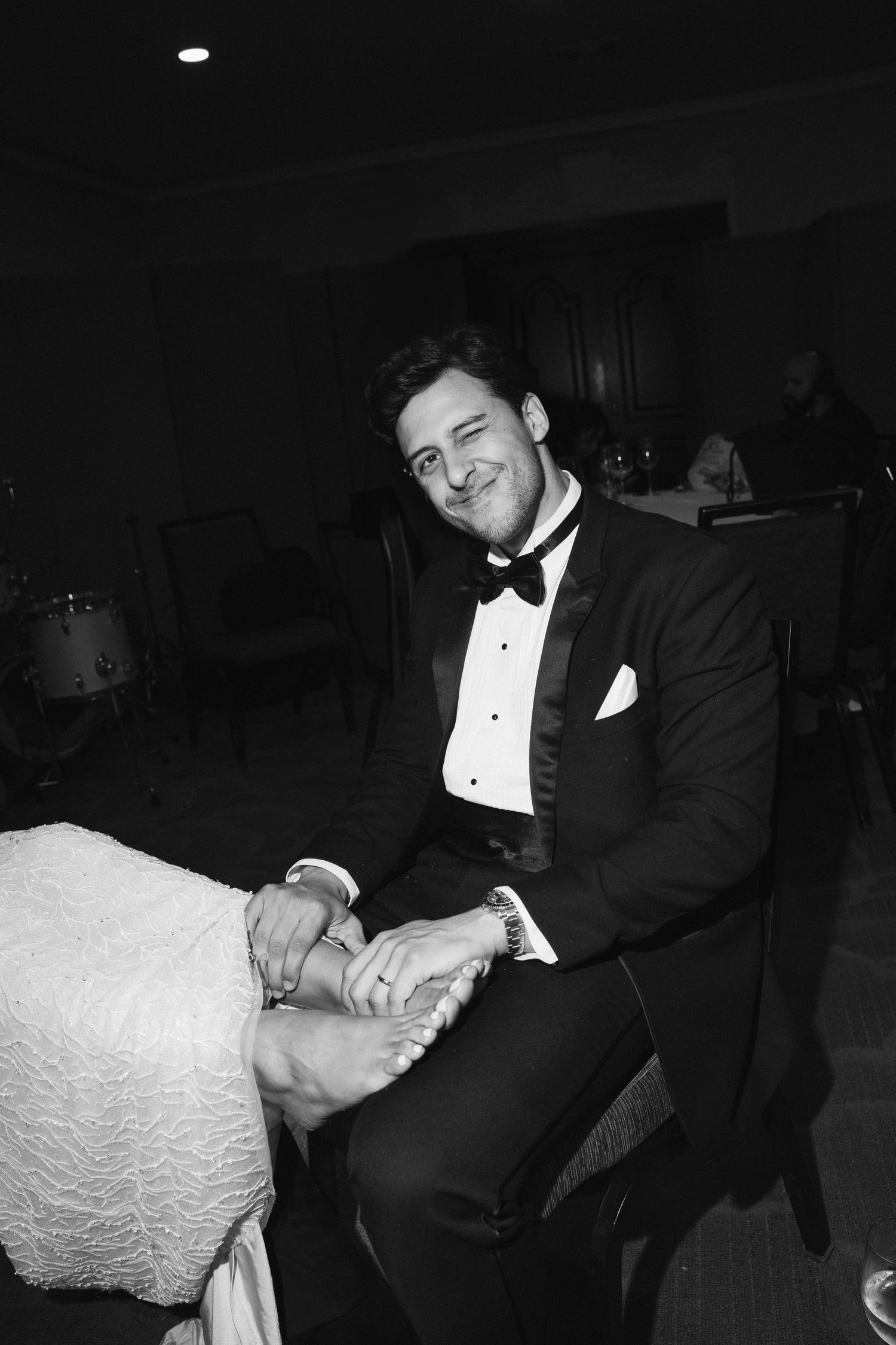 Classic black and white portrait of a groom in formal tuxedo attire.