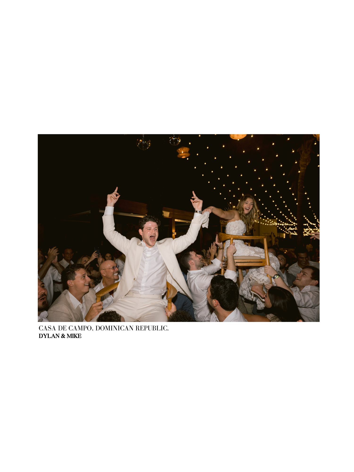 Wedding guests celebrate on the dance floor during a joyful reception with string lights overhead.