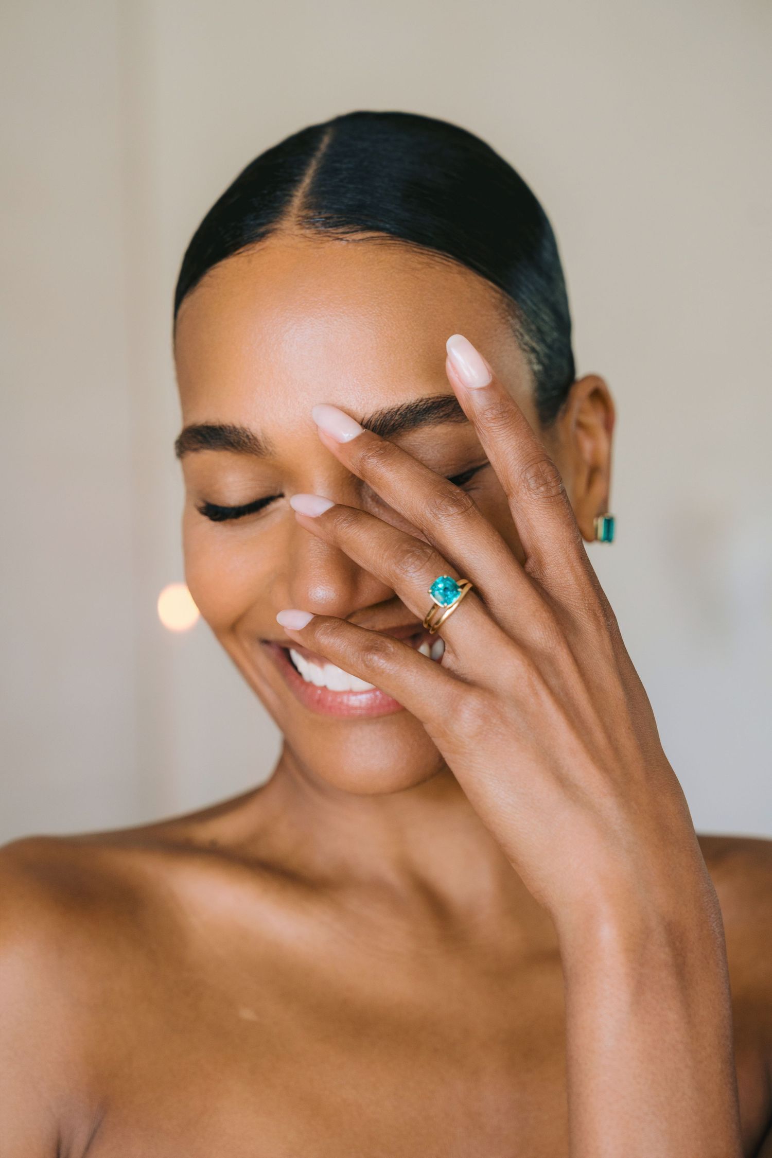 Portrait photo showing a joyful smile and delicate hand gesture with turquoise jewelry and white manicured nails.