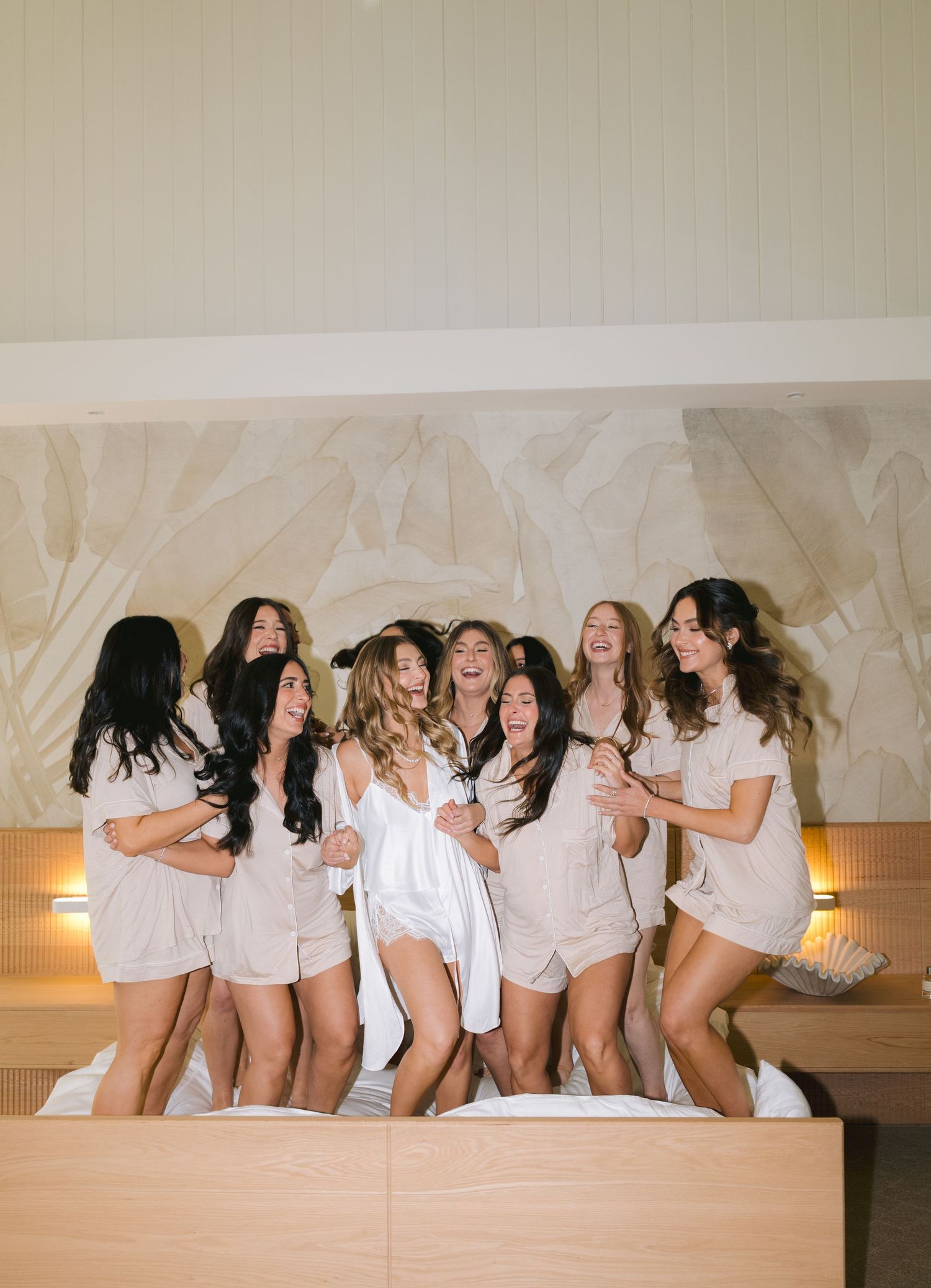 A group of people wearing white tops pose together on a beige couch in a fun candid photo sequence.
