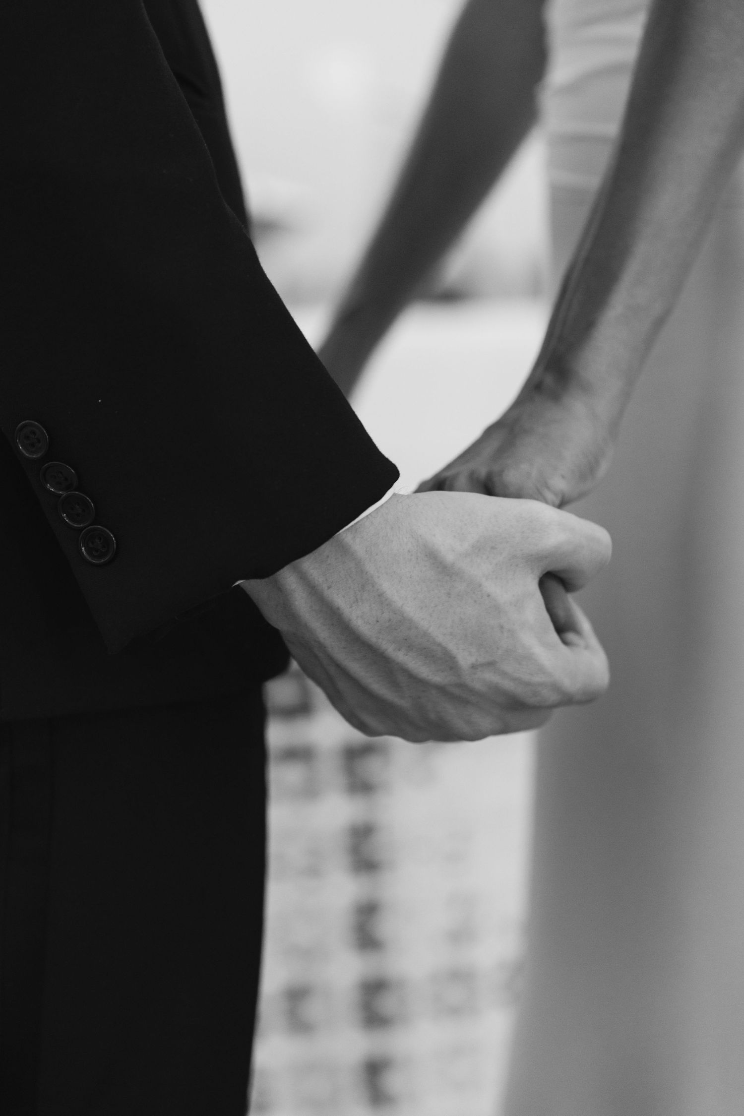 Close-up sequence of hands putting on formal black suit jacket sleeves in black and white.