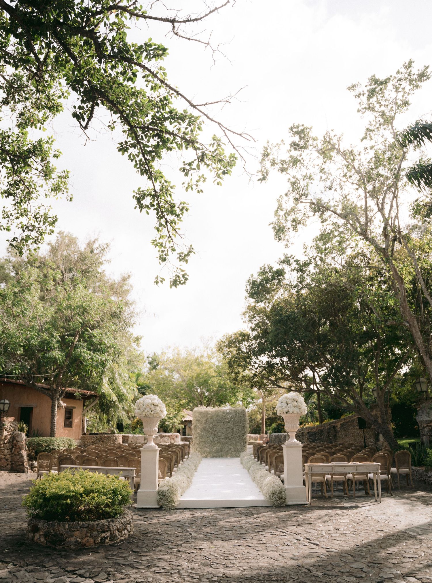 Stone pathway leading to wedding ceremony setup through lush garden archway.