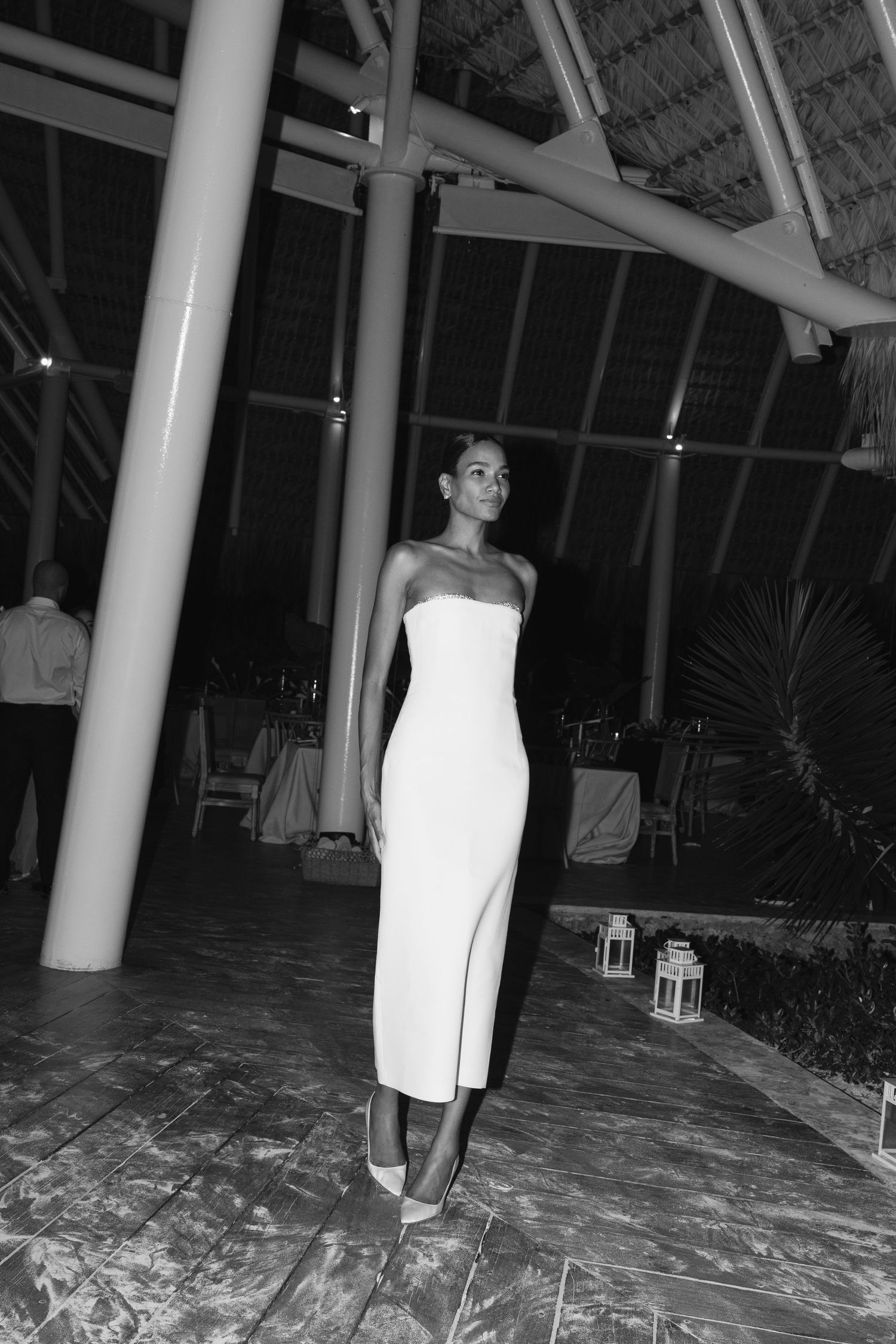 Elegant long white strapless dress photographed in black and white at an indoor venue with architectural columns.