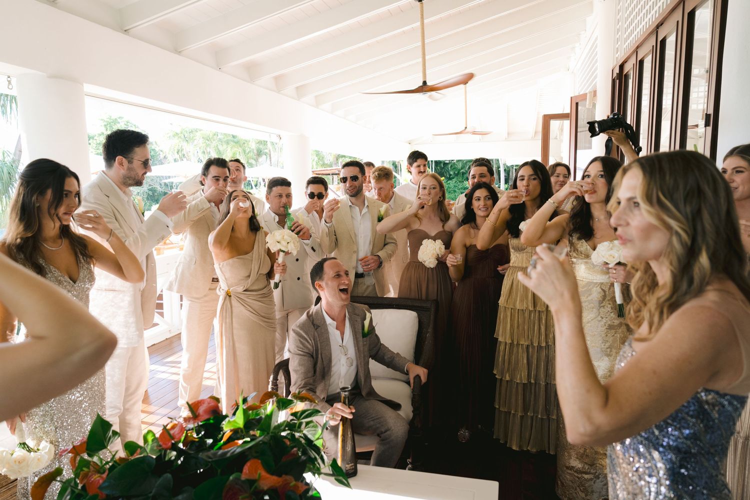 A wedding celebration with guests dancing and celebrating in a light-filled reception venue.