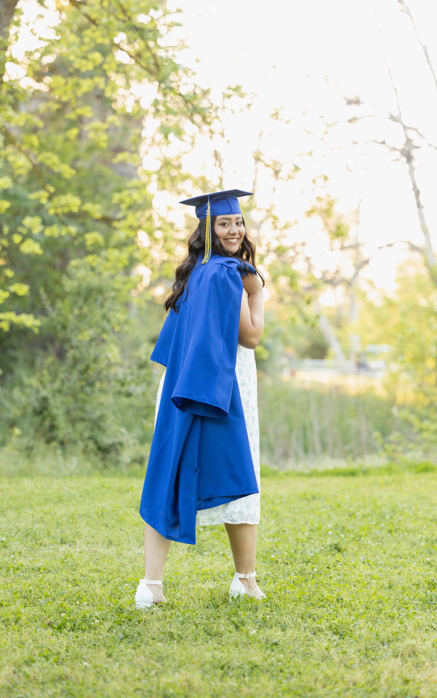 high school senior wearing graduation cap while holding gown over her shoulder