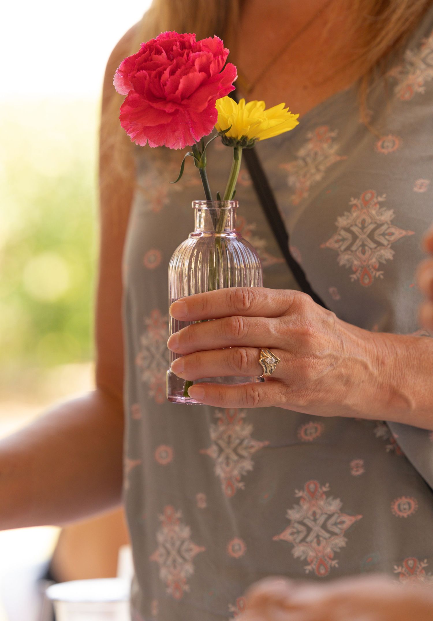 woman holding small vase with 2 flowers
