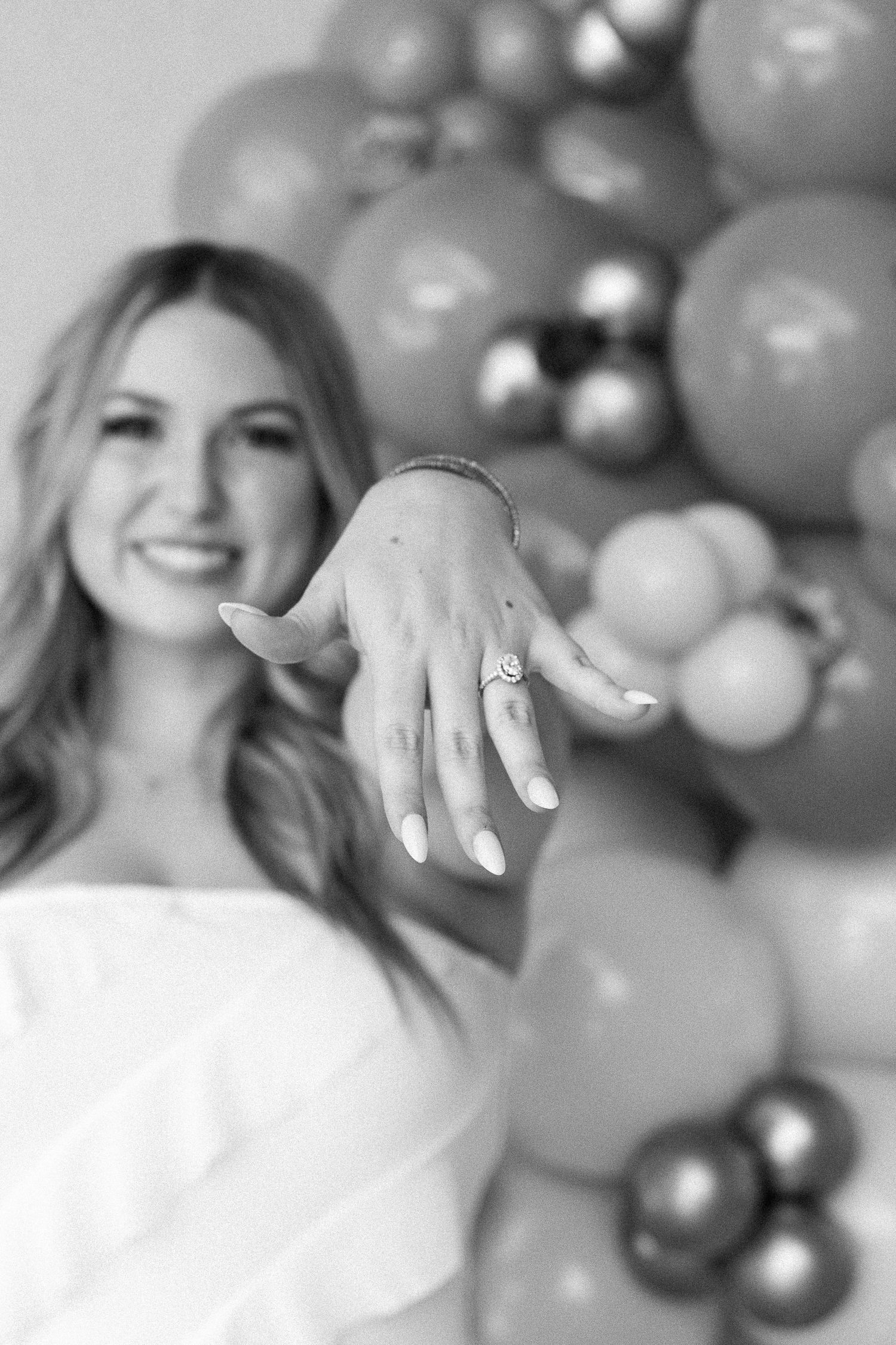 woman holding hand out in front of her showing off her engagement ring in black and white