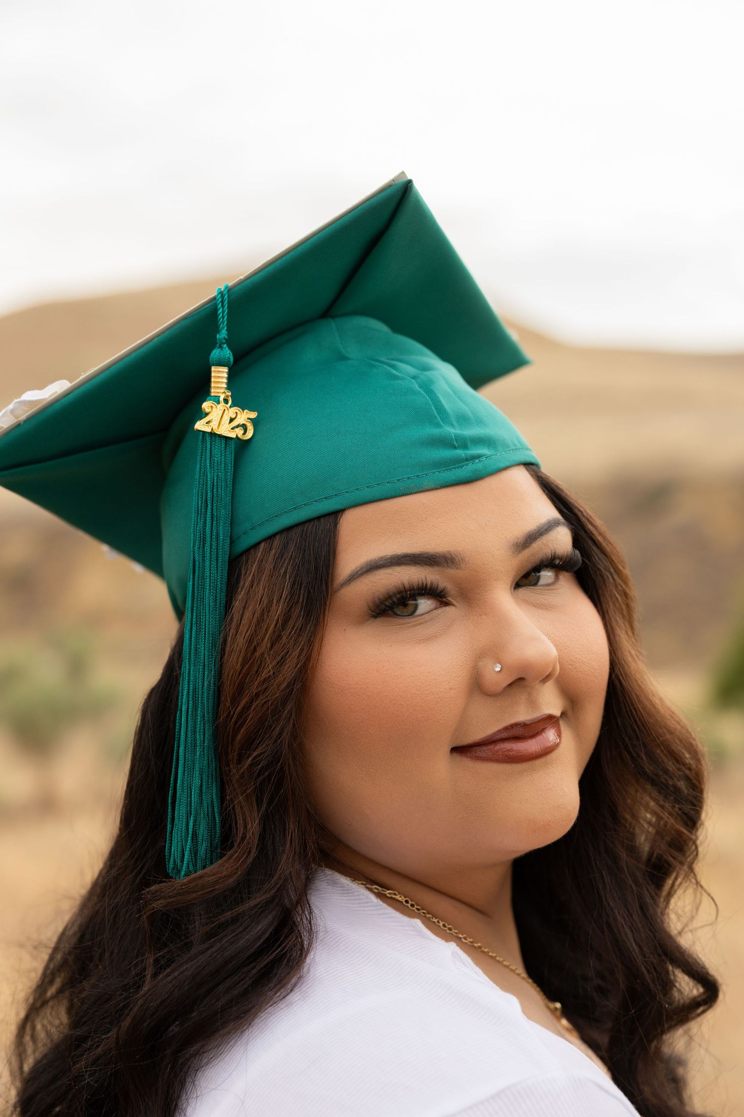 high school senior looking over her shoulder with graduation cap on