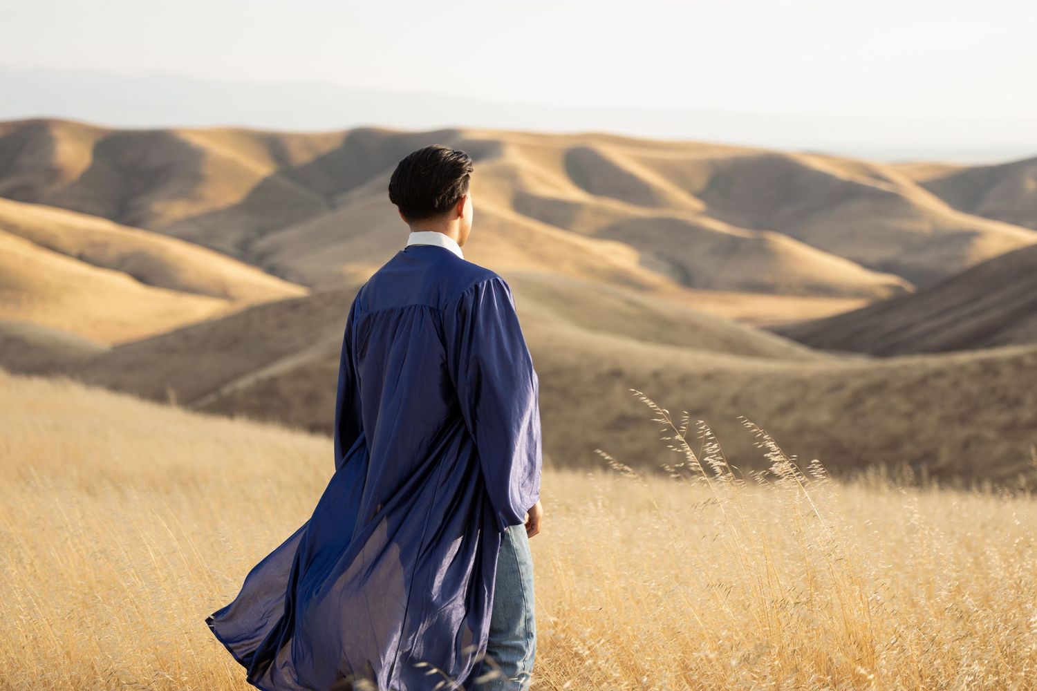 high school senior standing facing away with graduation gown on