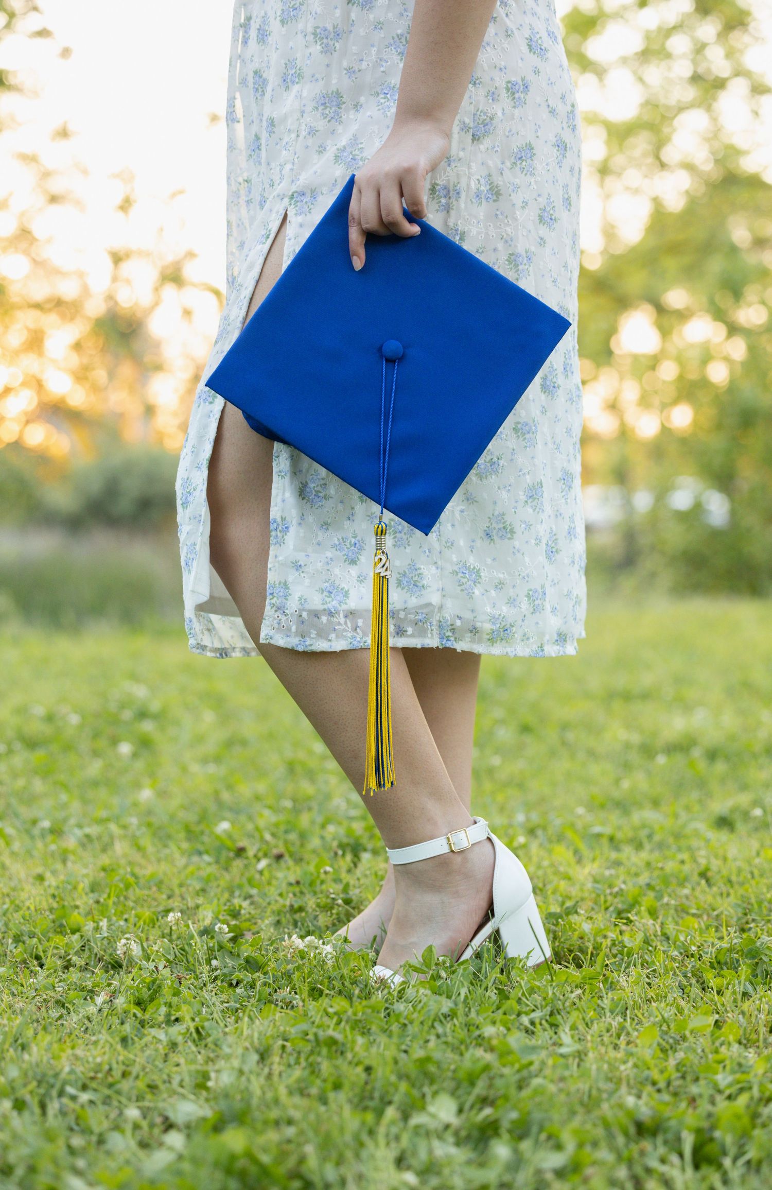 high school senior holding graduation cap by her side