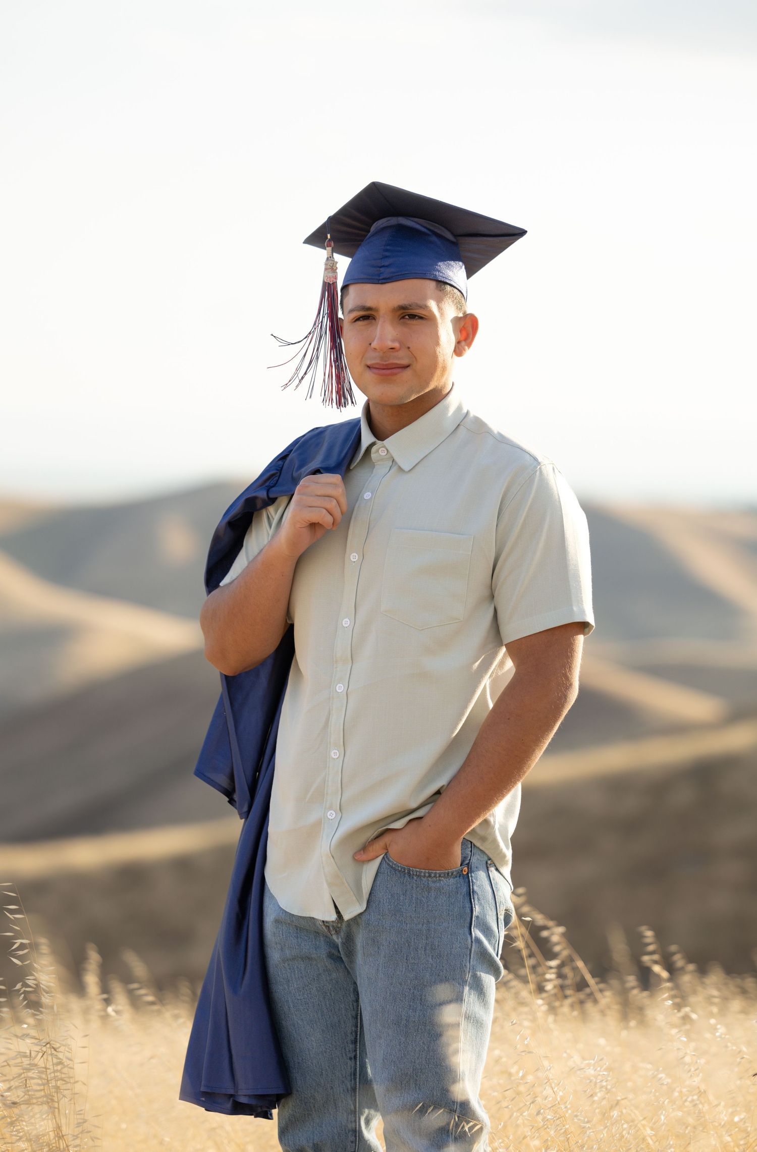 high school senior standing with graduation cap on with gown over his should