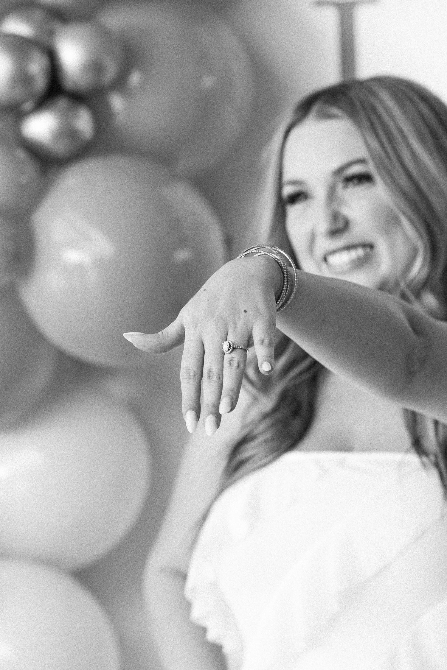 woman holding hand out in front of her showing off her engagement ring in black and white