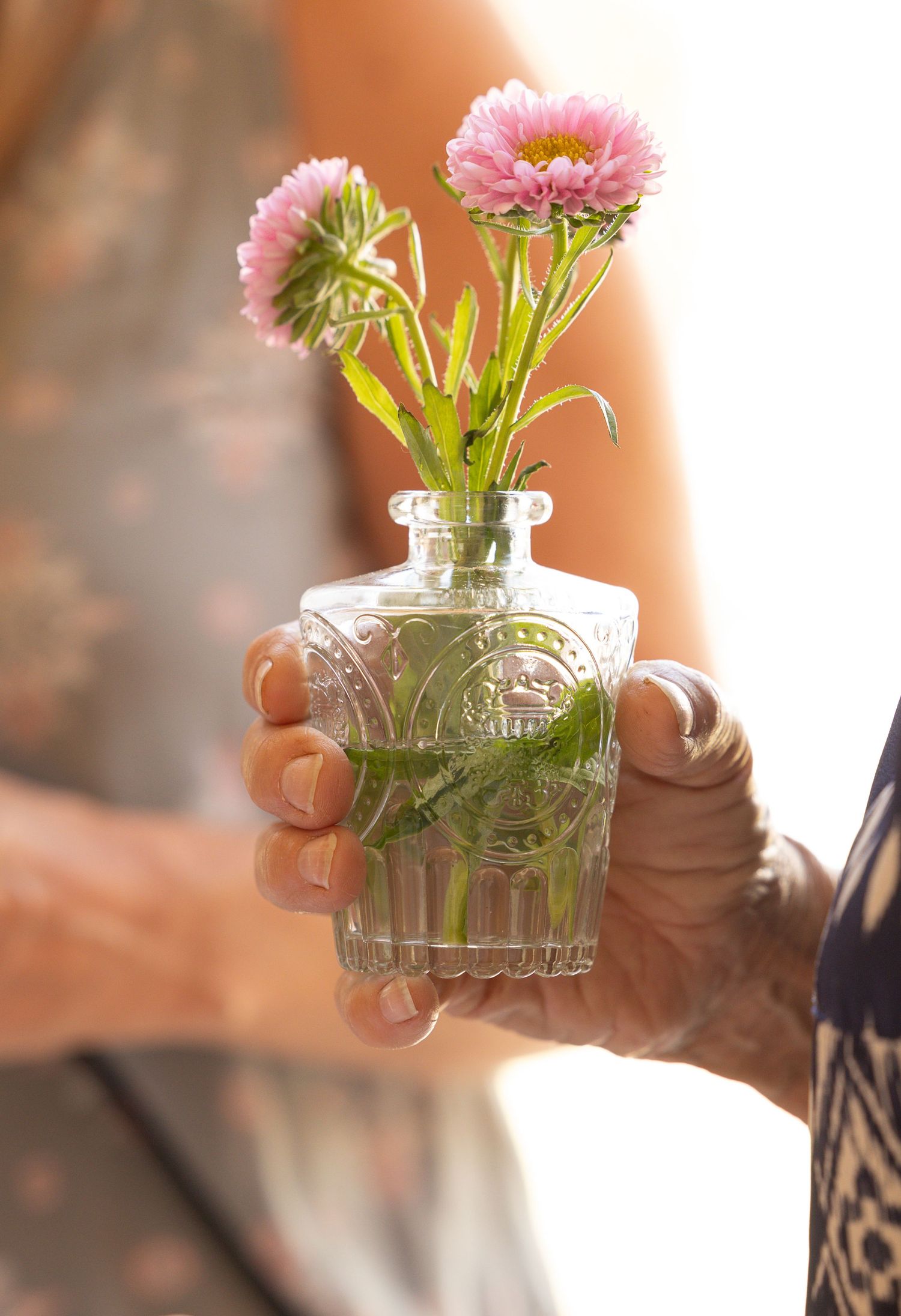 woman holding small vase with 2 flowers