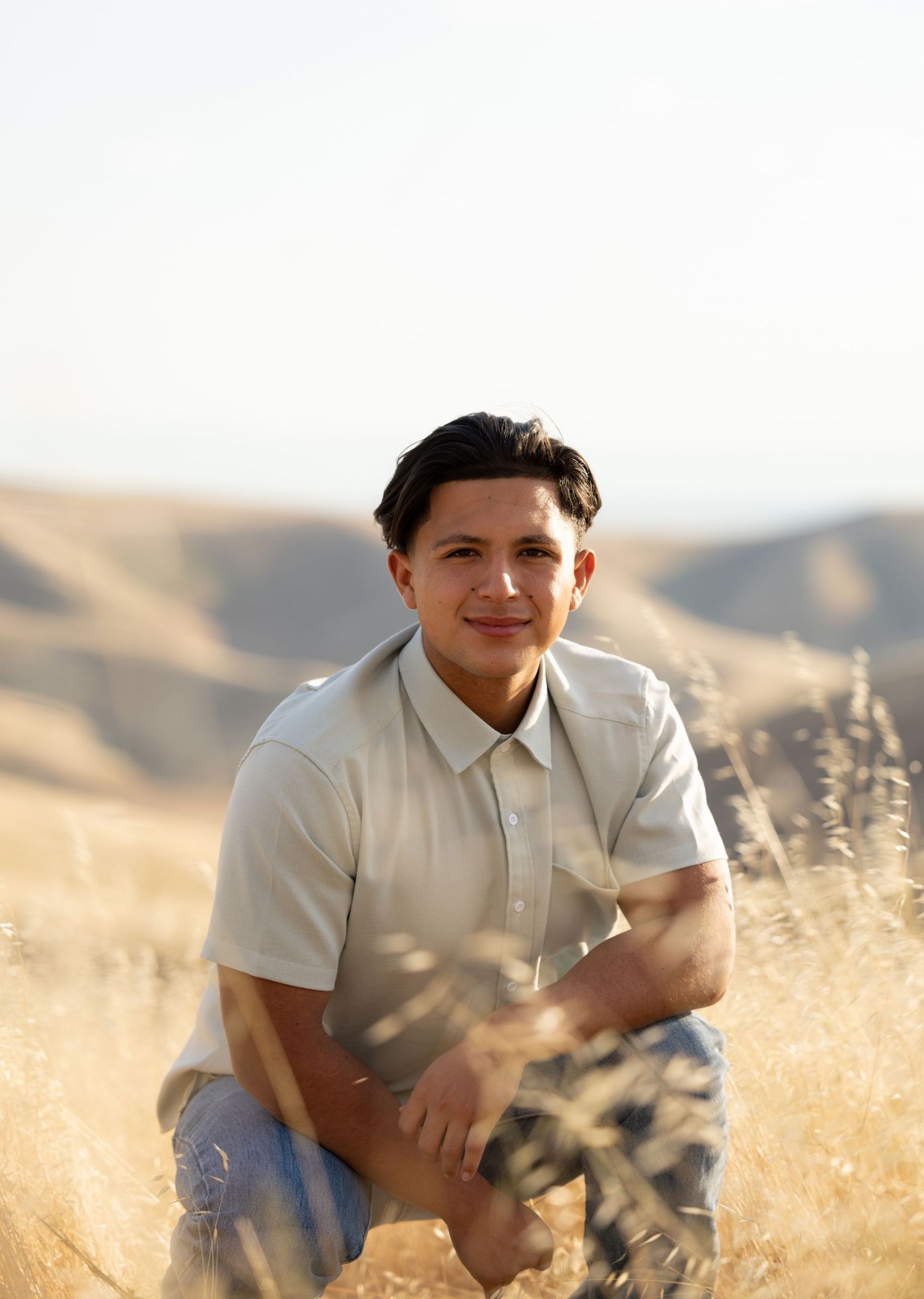 high school senior crouching down in weeds