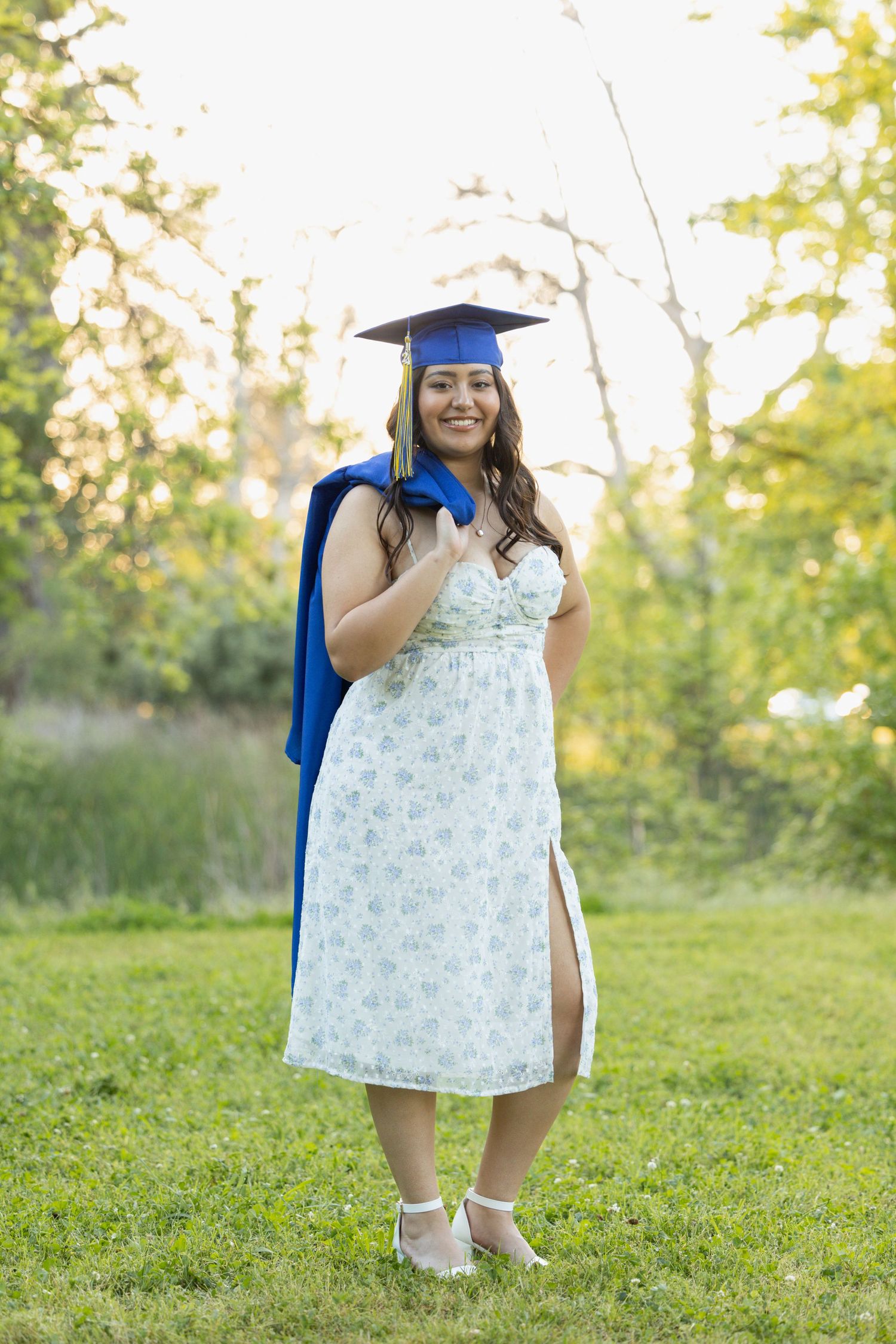 high school senior wearing graduation cap while holding gown over her shoulder