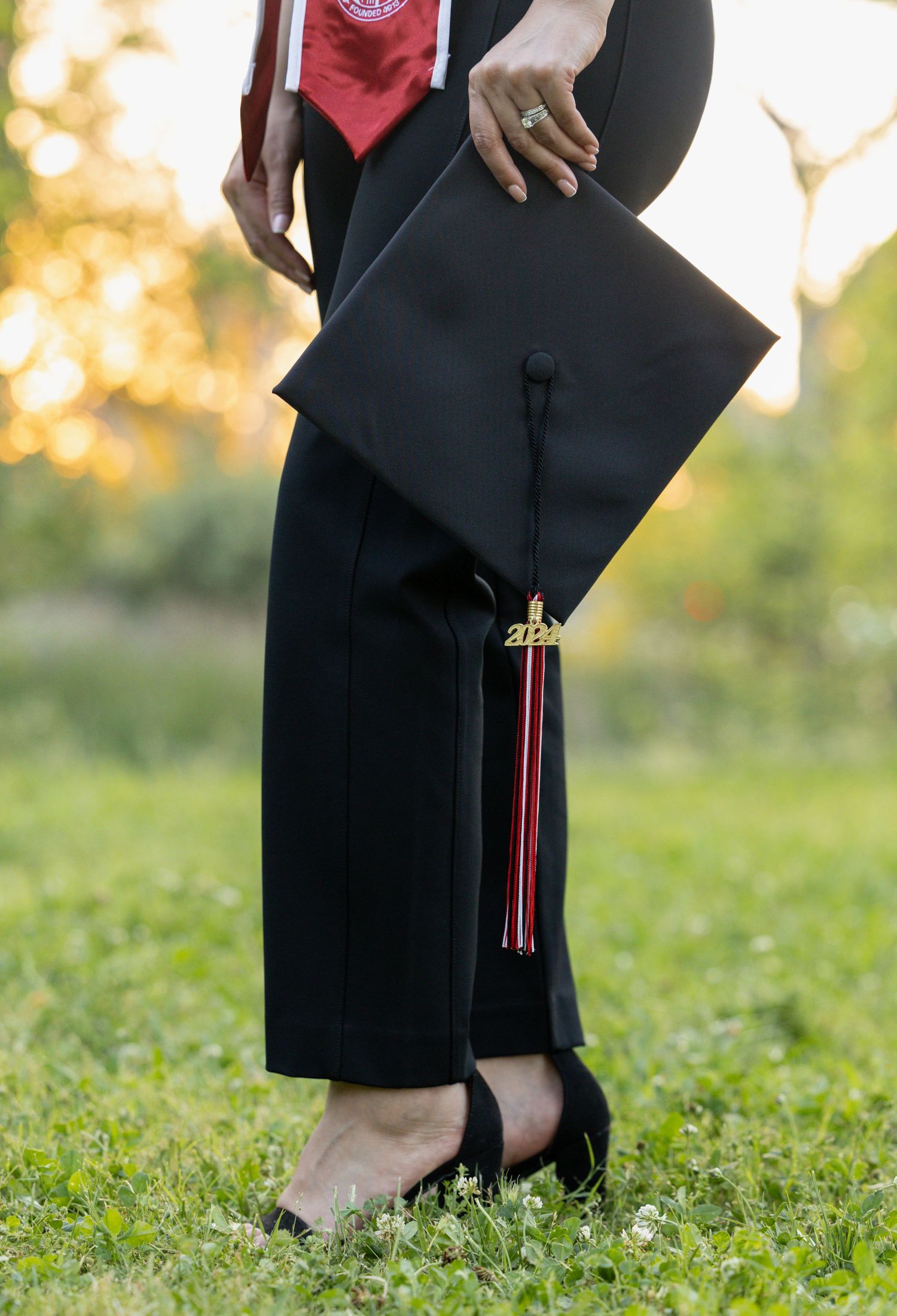 college senior holding graduation cap by her side