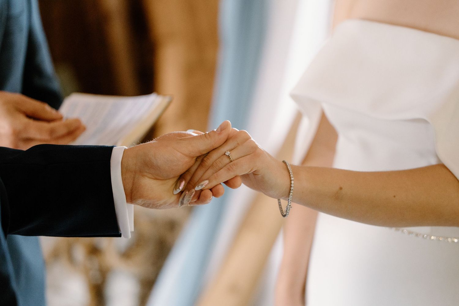 Close-up of hands exchanging rings during wedding ceremony in rustic venue.