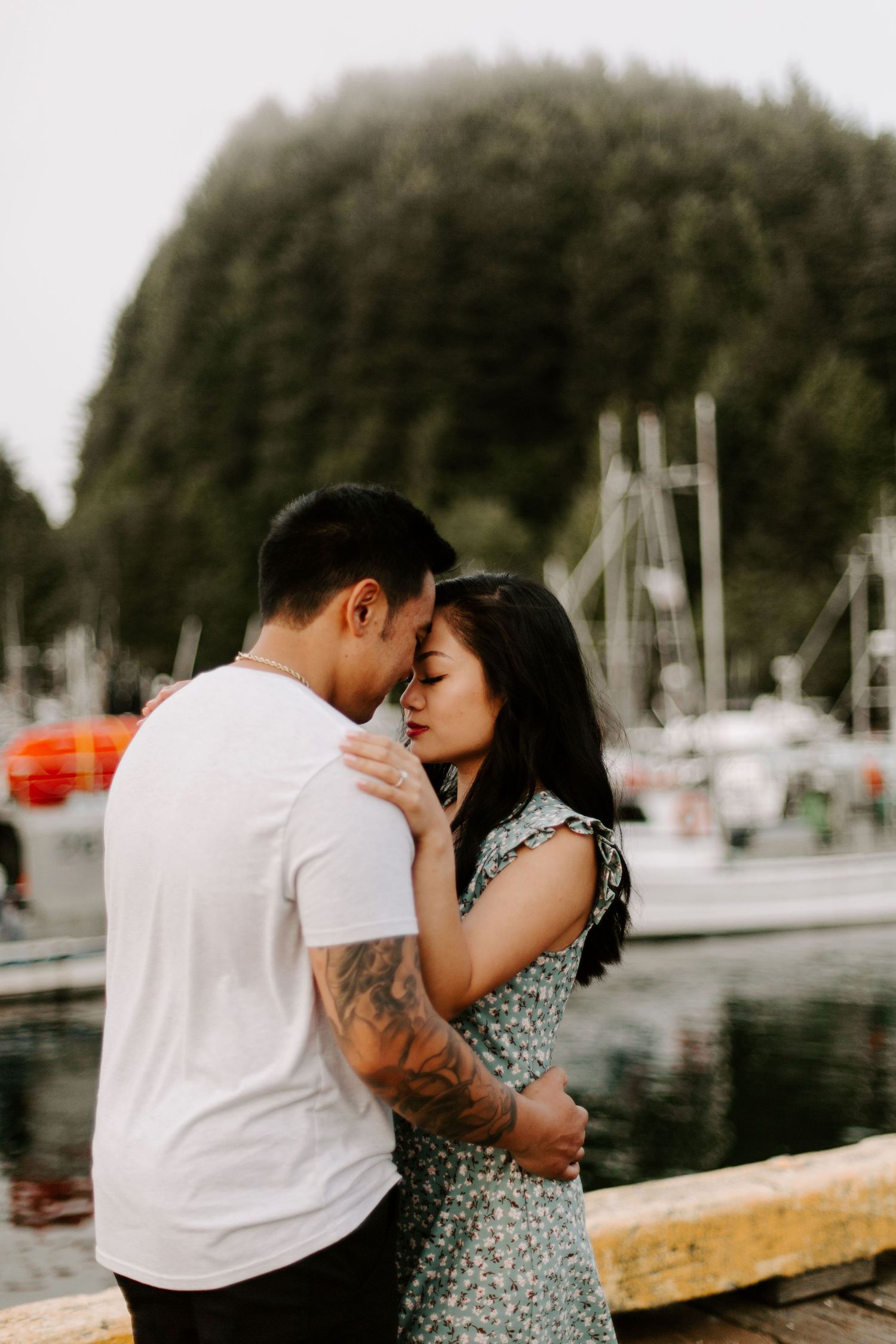 Romantic moment captured between a couple by a marina with boats in the background.