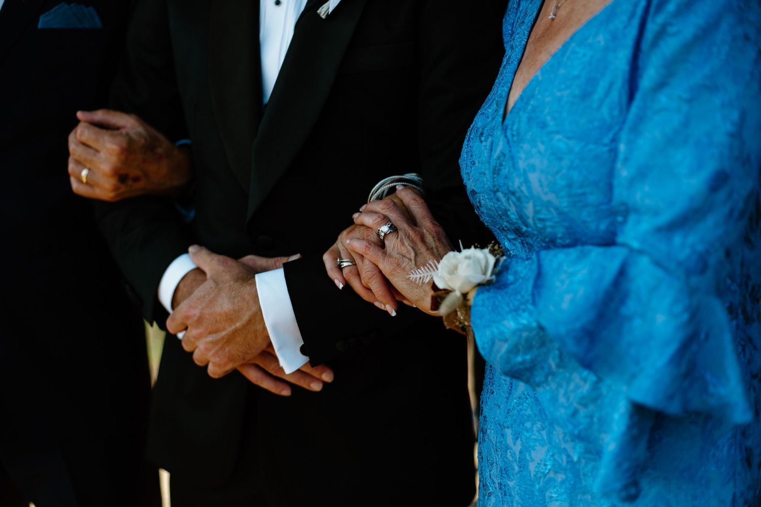 Close-up of formal attire and corsages at a wedding ceremony.