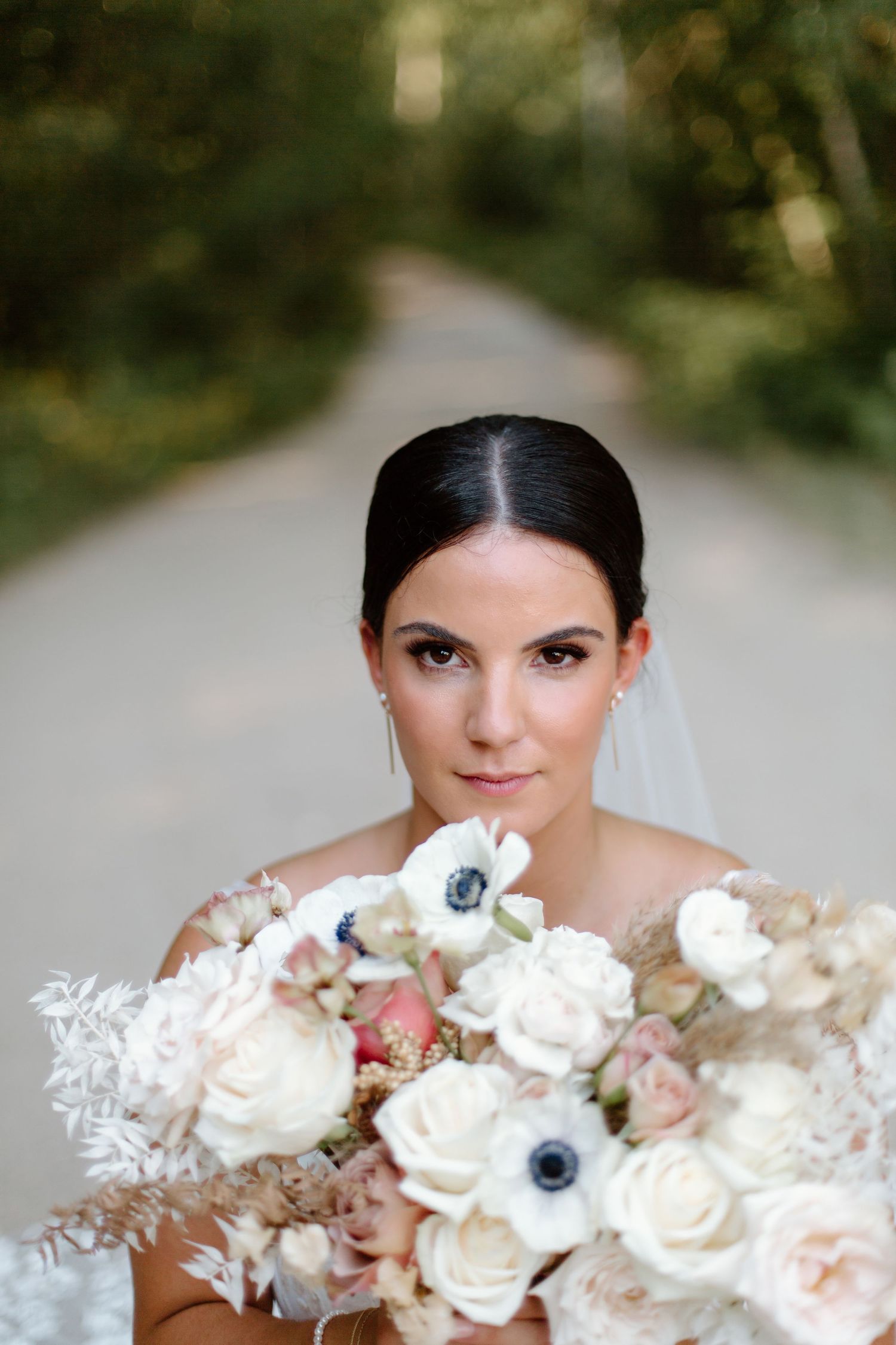 A bride poses with a stunning white and blush floral bouquet featuring anemones and roses in a candid photo series.