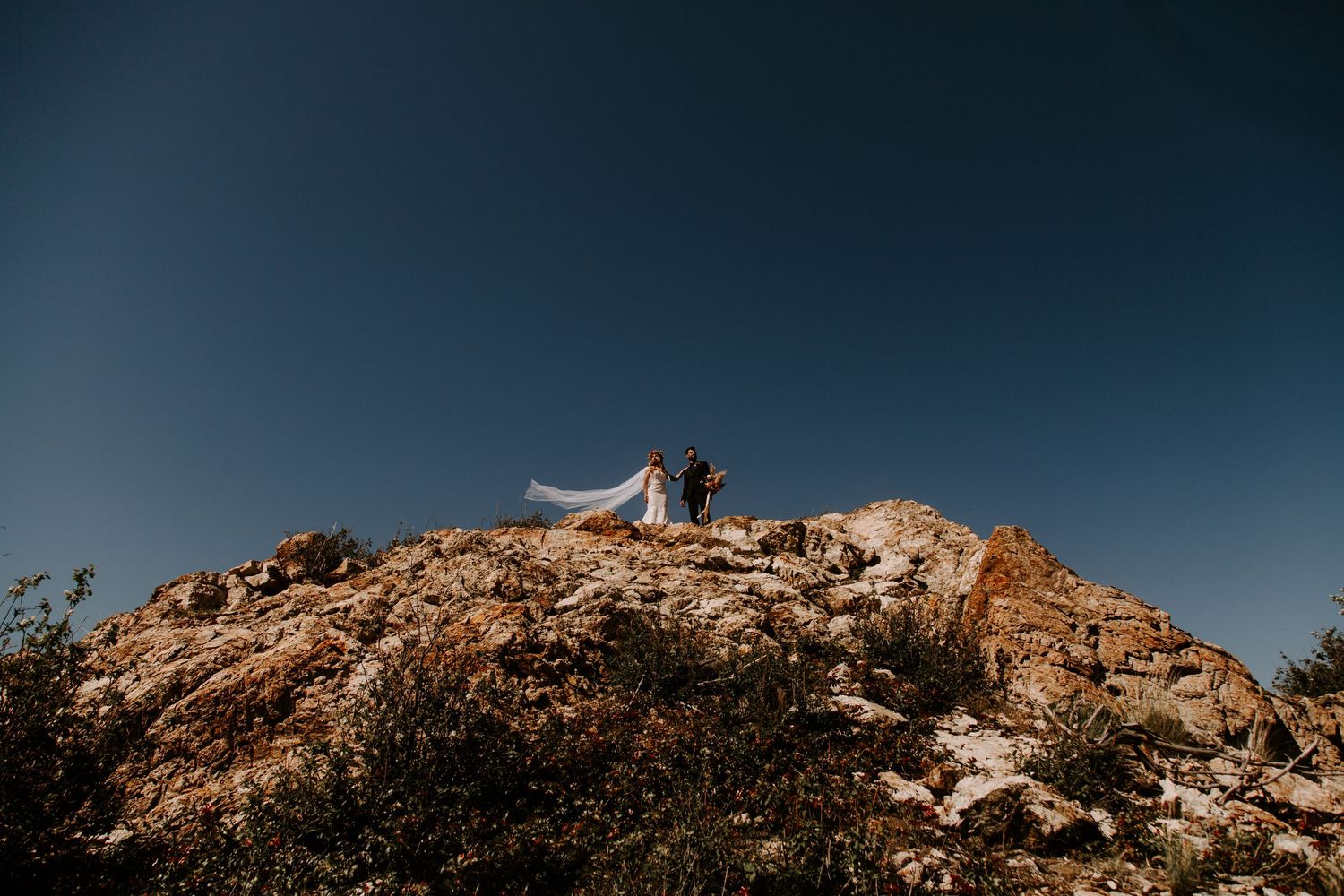 A scenic mountaintop wedding ceremony set against a dramatic blue sky.