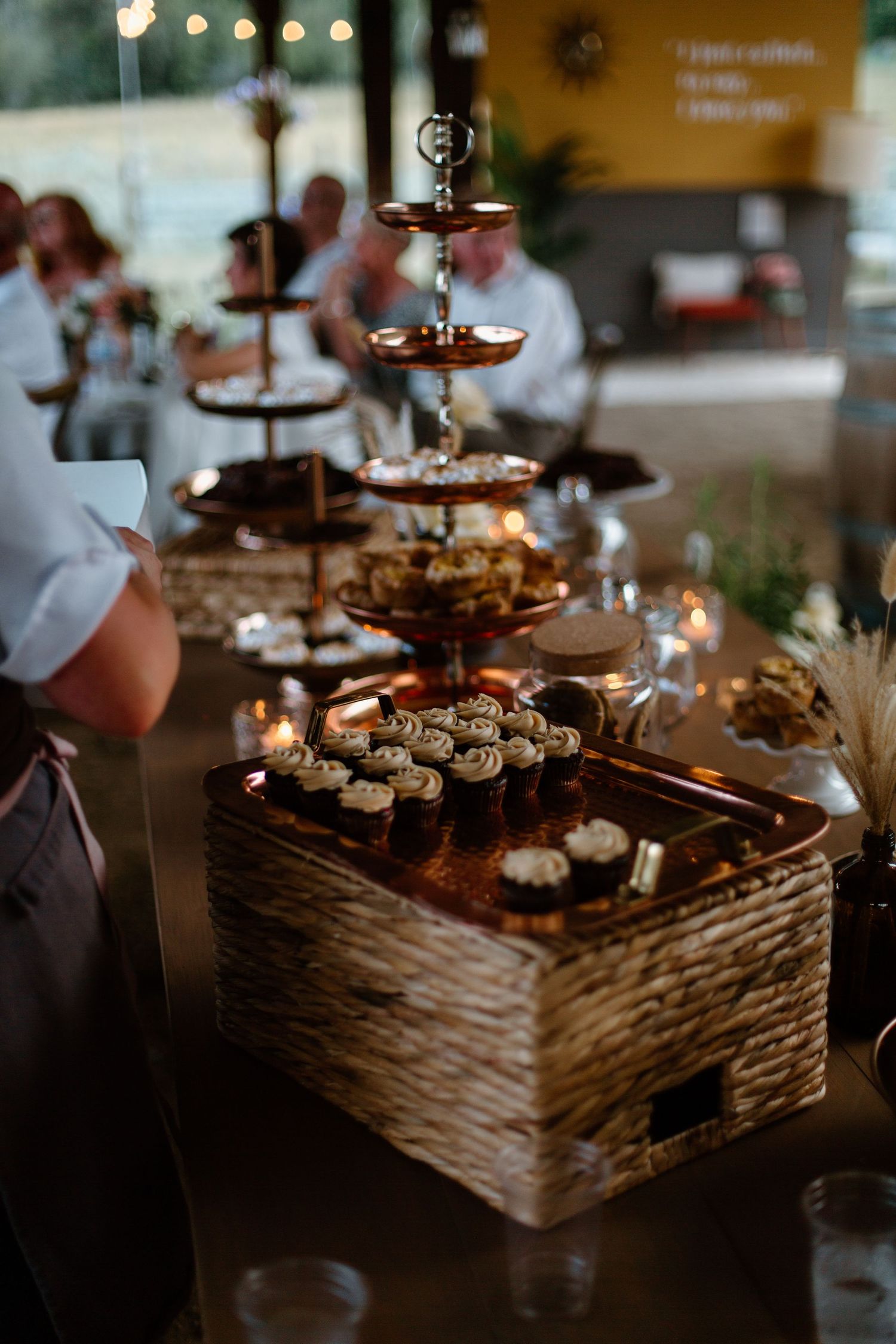 A tiered display of cupcakes and desserts at a rustic wedding reception.