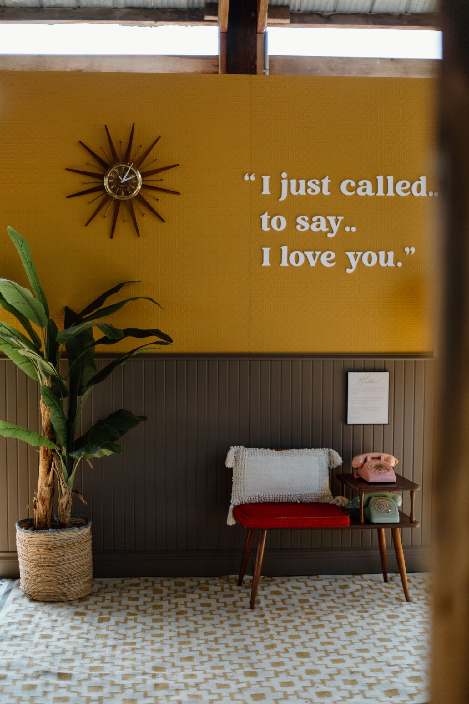 Mid-century modern decor with yellow wall, retro clock, and 'I love you' quote text.