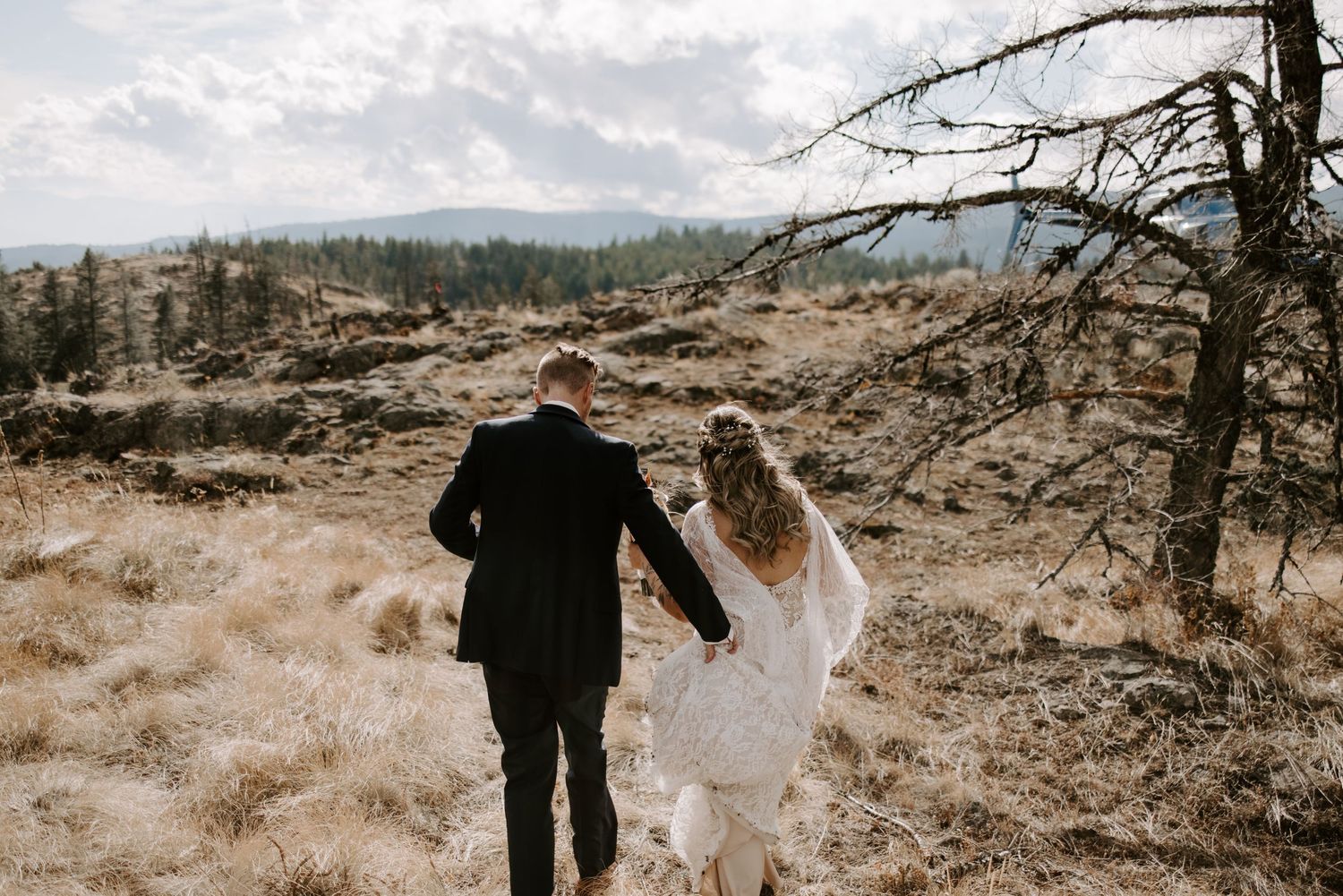 A couple walking hand in hand through a rugged mountain landscape.