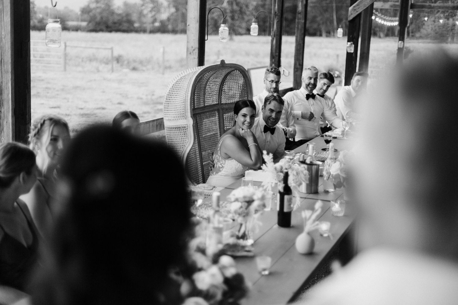 Wedding guests gather outdoors under a covered patio area during a celebration event.