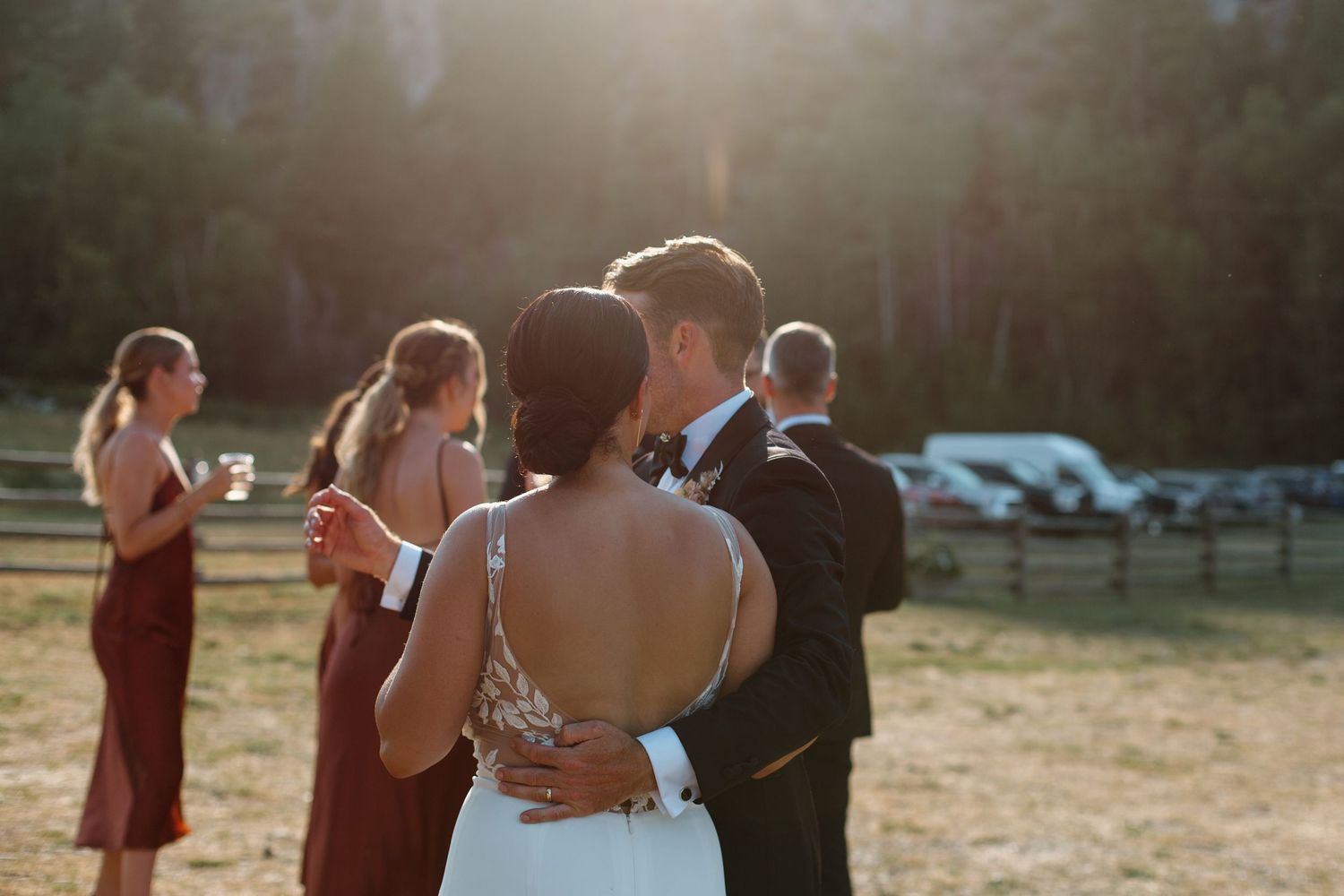 A couple shares an intimate moment during their wedding dance outdoors at sunset.
